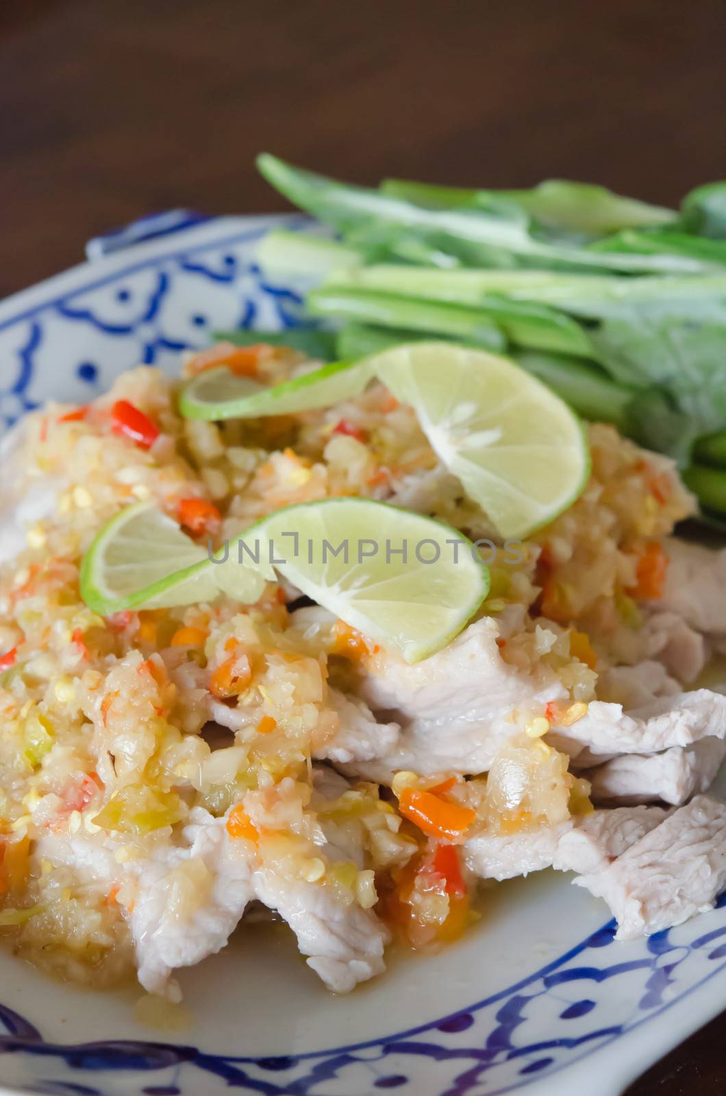 close up spicy pork served with chili sauce ,  fresh lemon and vegetable