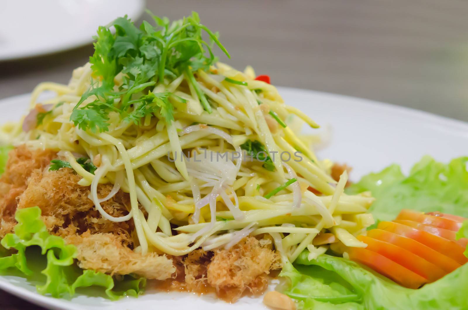 Crispy catfish salad with green mango and vegetable , served with tomato and lettuce