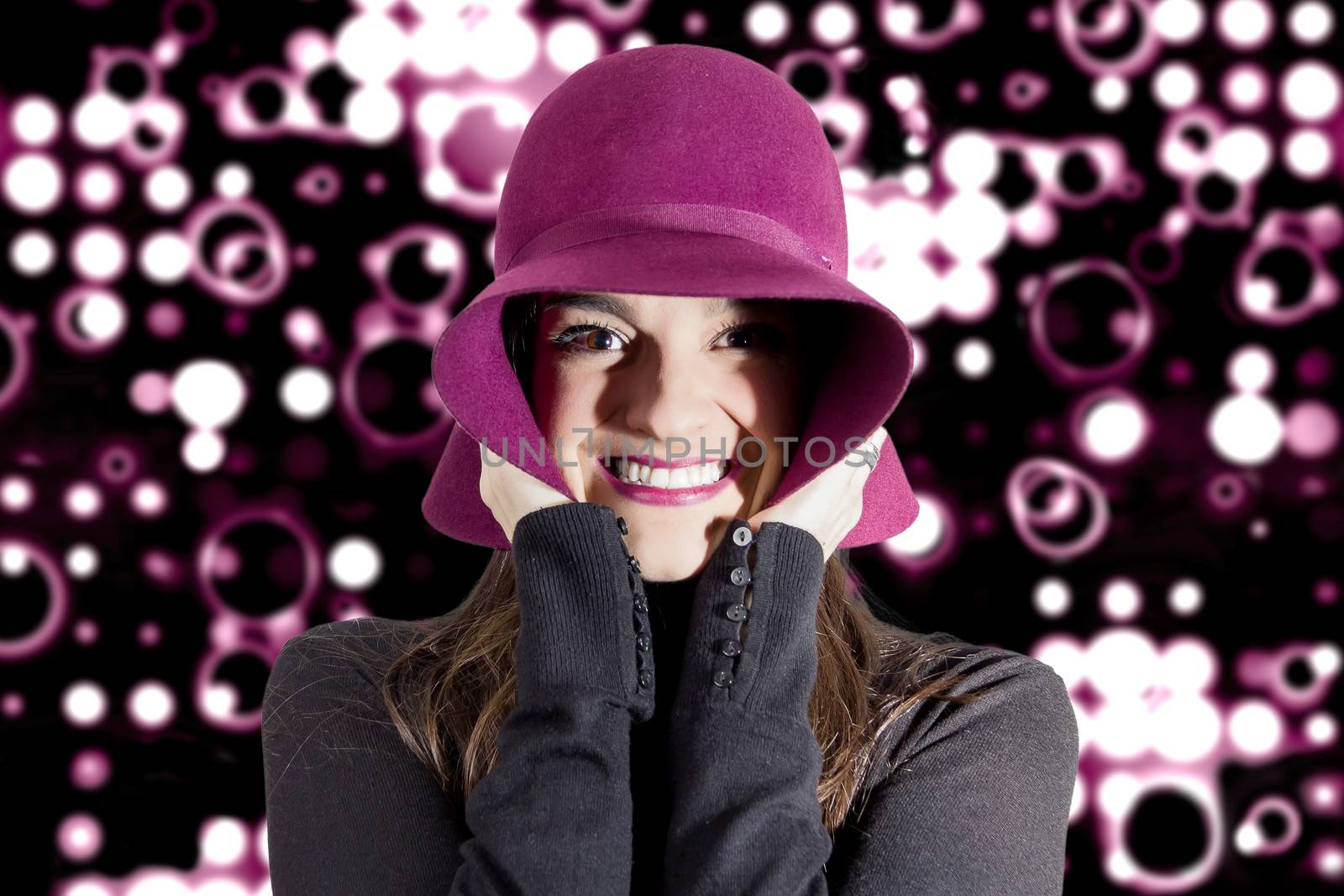 Portrait of beautiful young girl with a garnet hat on her head, in front of spotlights background