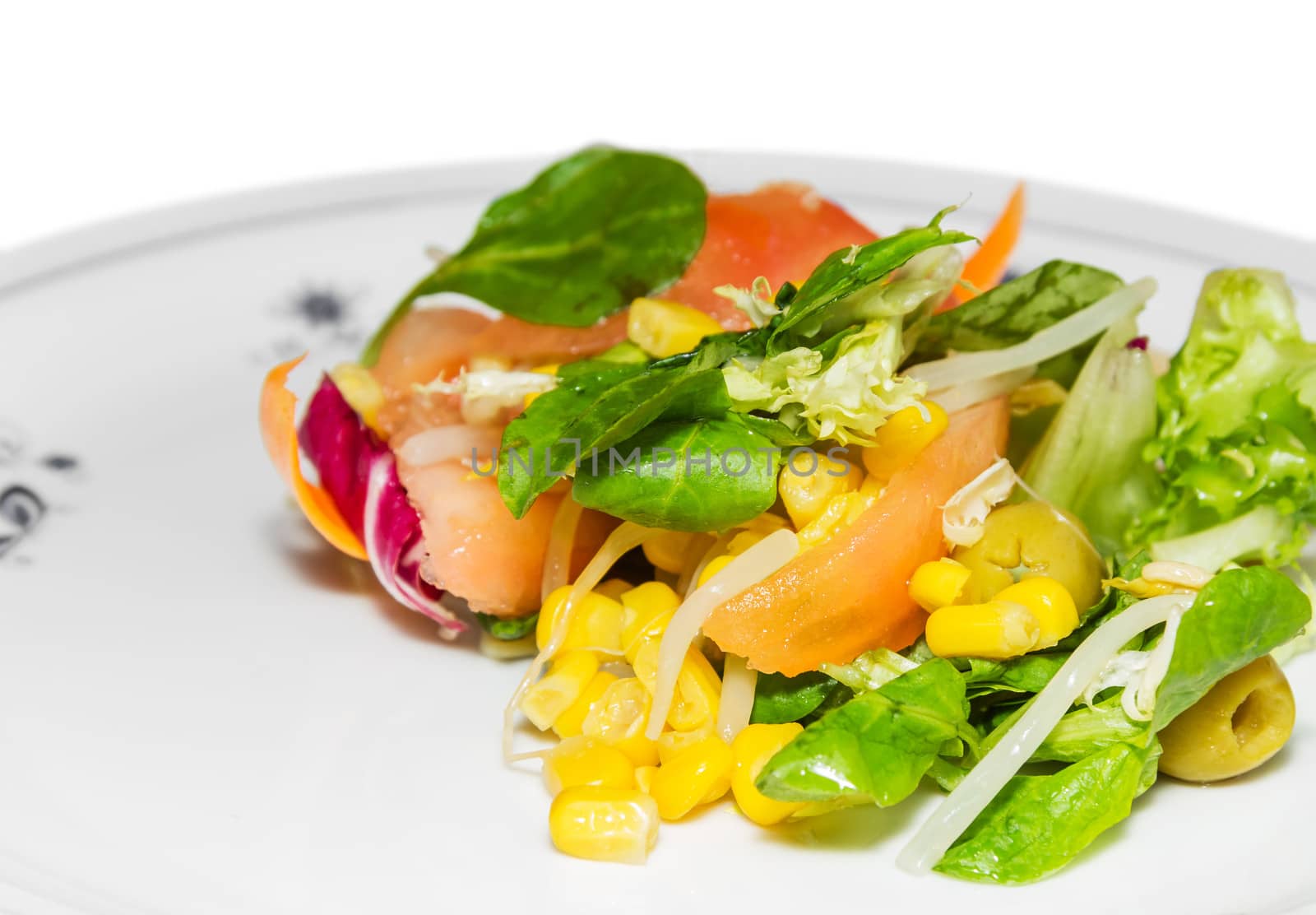 Closeup of fresh mediterranean style salad with corn and olives, served in a plate