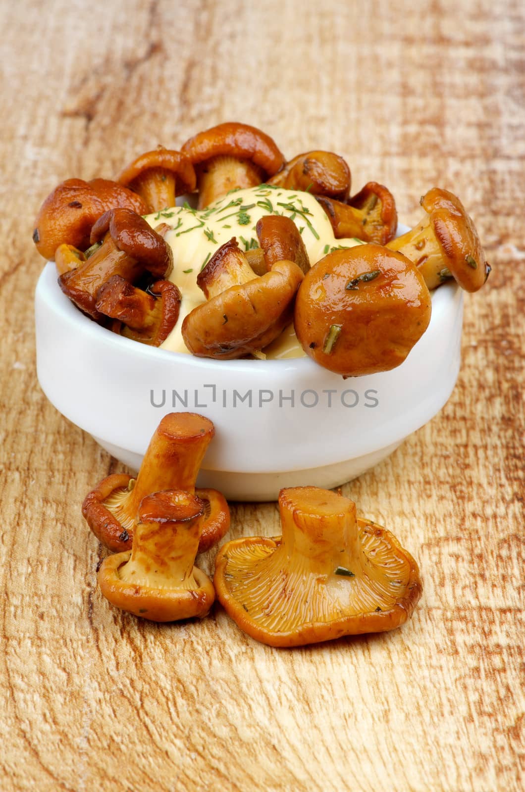 Snack of Delicious Roasted Chanterelles with Cheese Sauce in White Bowl on Wooden background