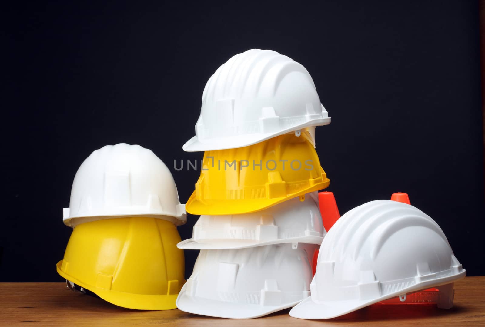 Stack of white and yellow helmets on black