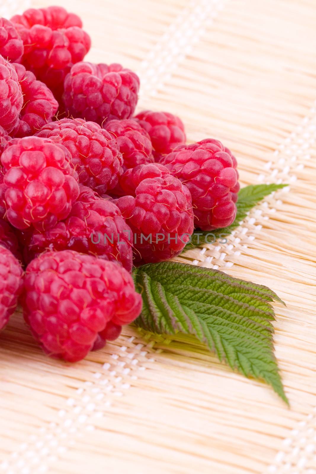 Closeup on fresh raspberries fruits on a straw mat
