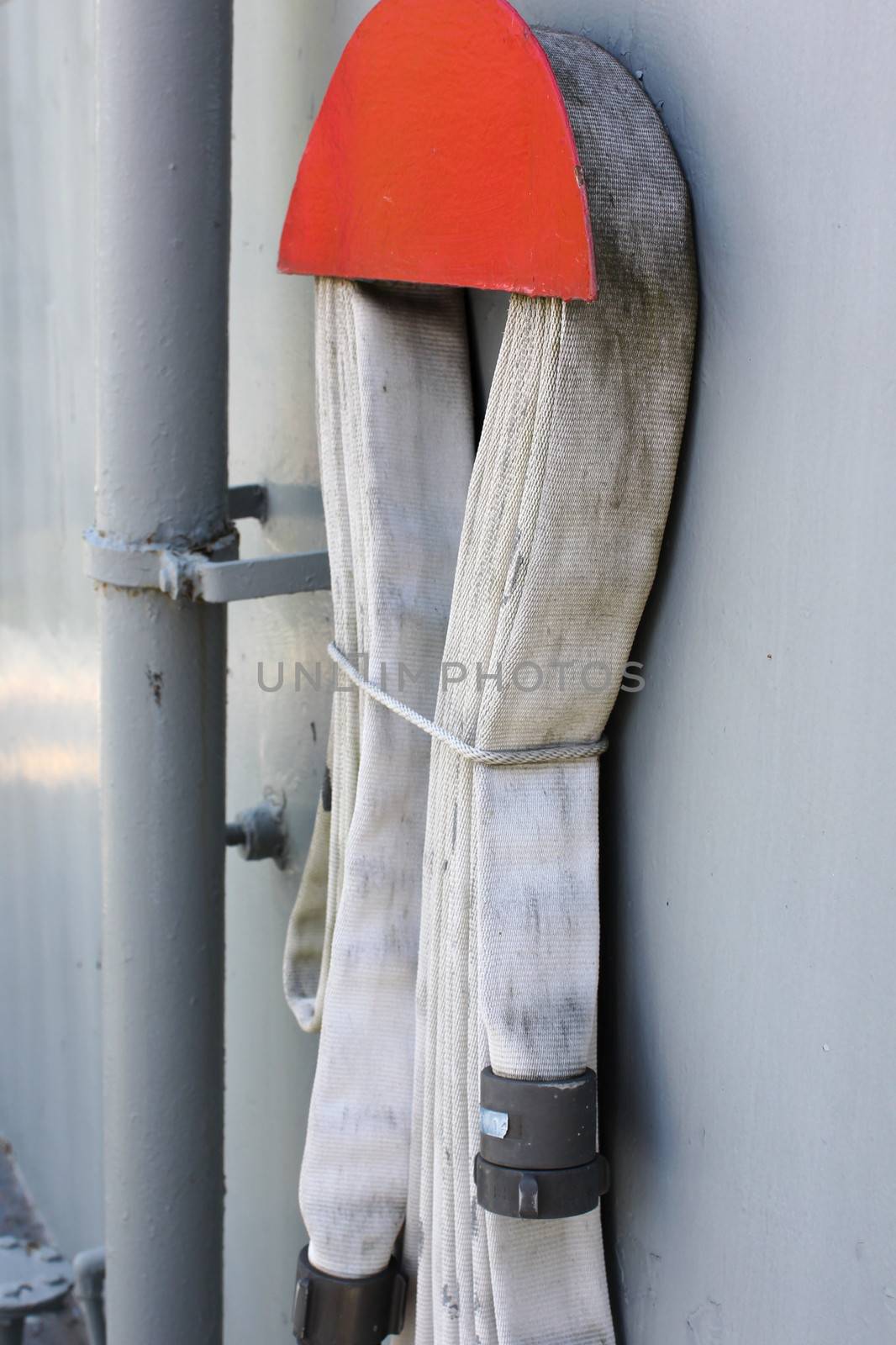 A fabric fire hose looped and stored on the wall of a ship.