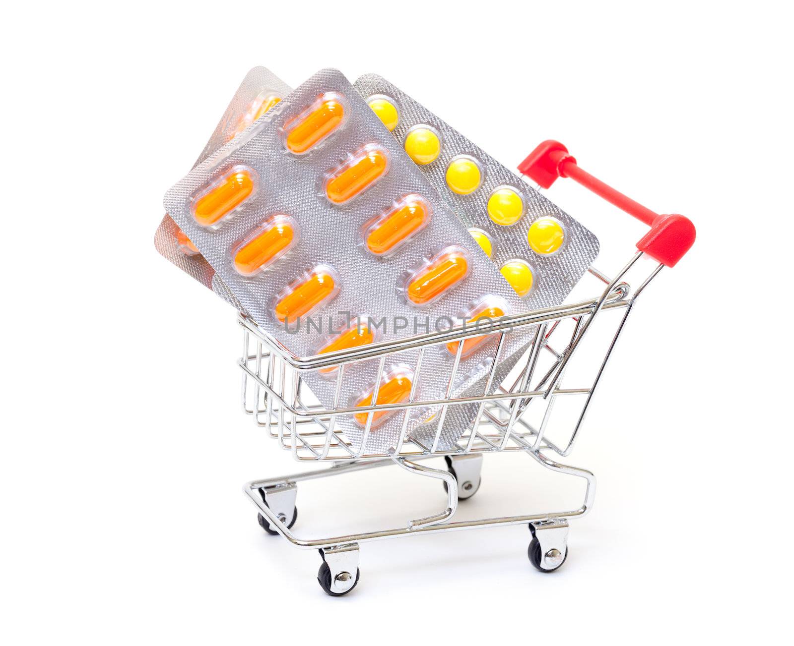Multicolored pills packs in shopping cart, on white background