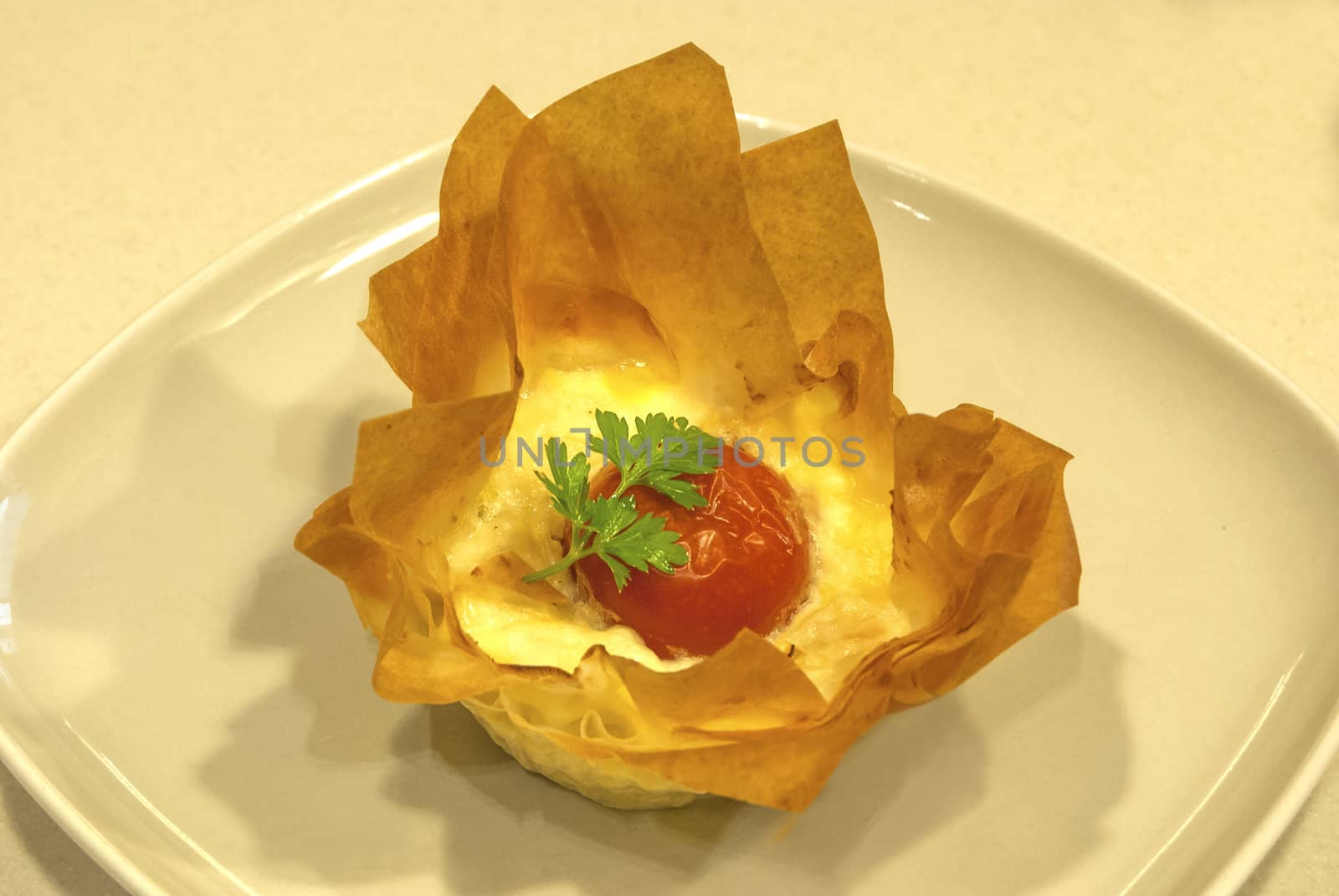 Small homemade pie with cheese and cherry tomato in a basket of pastry