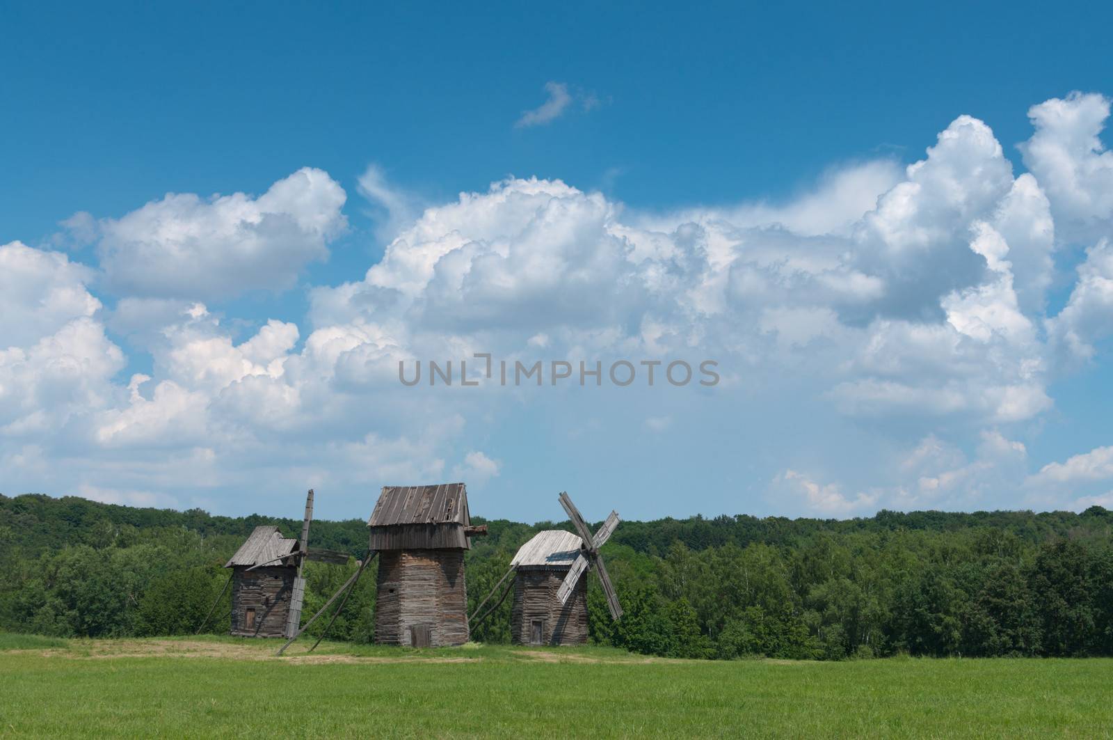 Three old wooden windmills on the field.