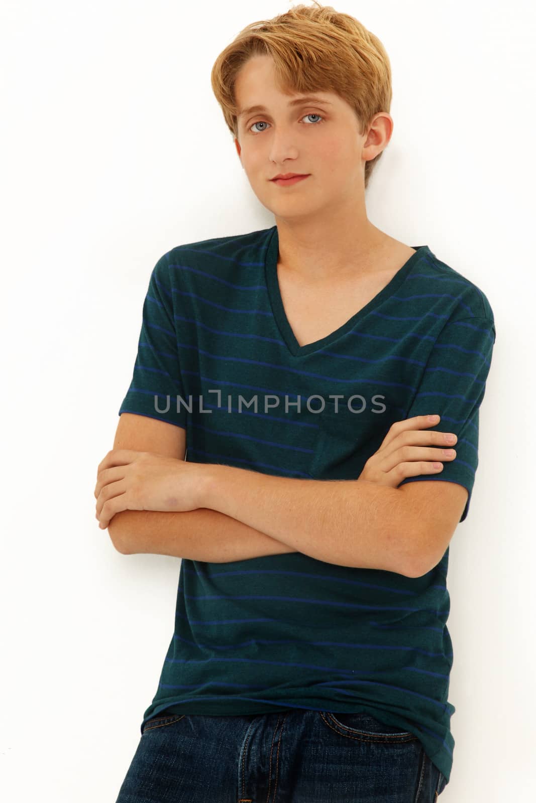 Attractive Teen Boy Caucasian leaning on wall with arms crossed.