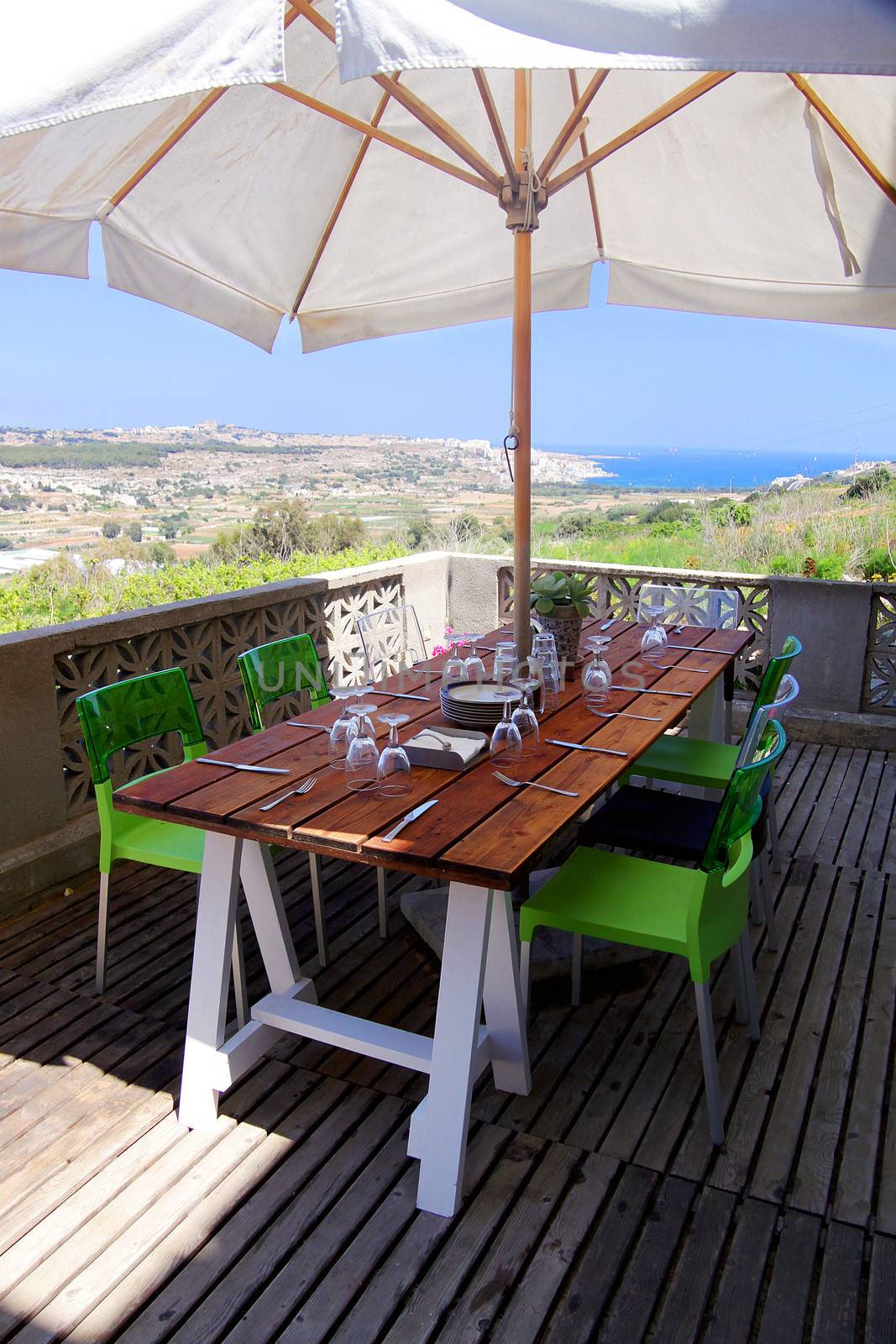 A terrace overlooking the sea with a table set for lunch or dinner
