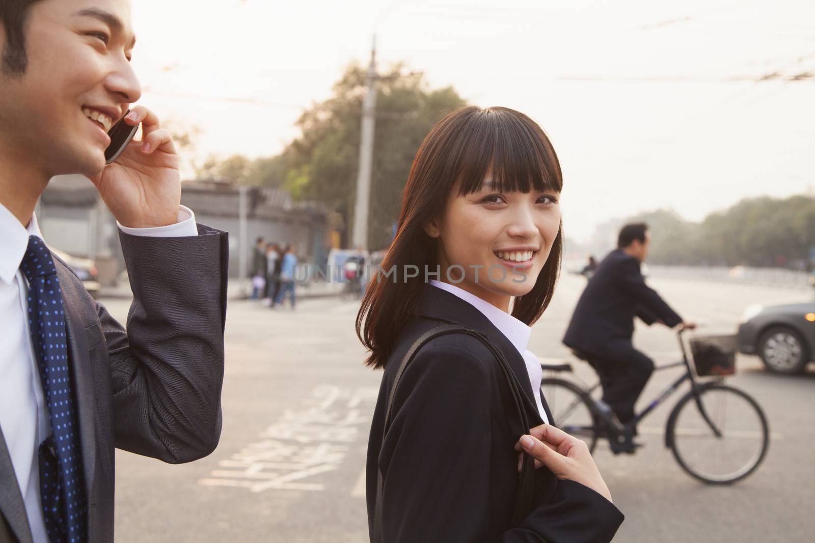 Two young business people outside on the street using phone in Beijing