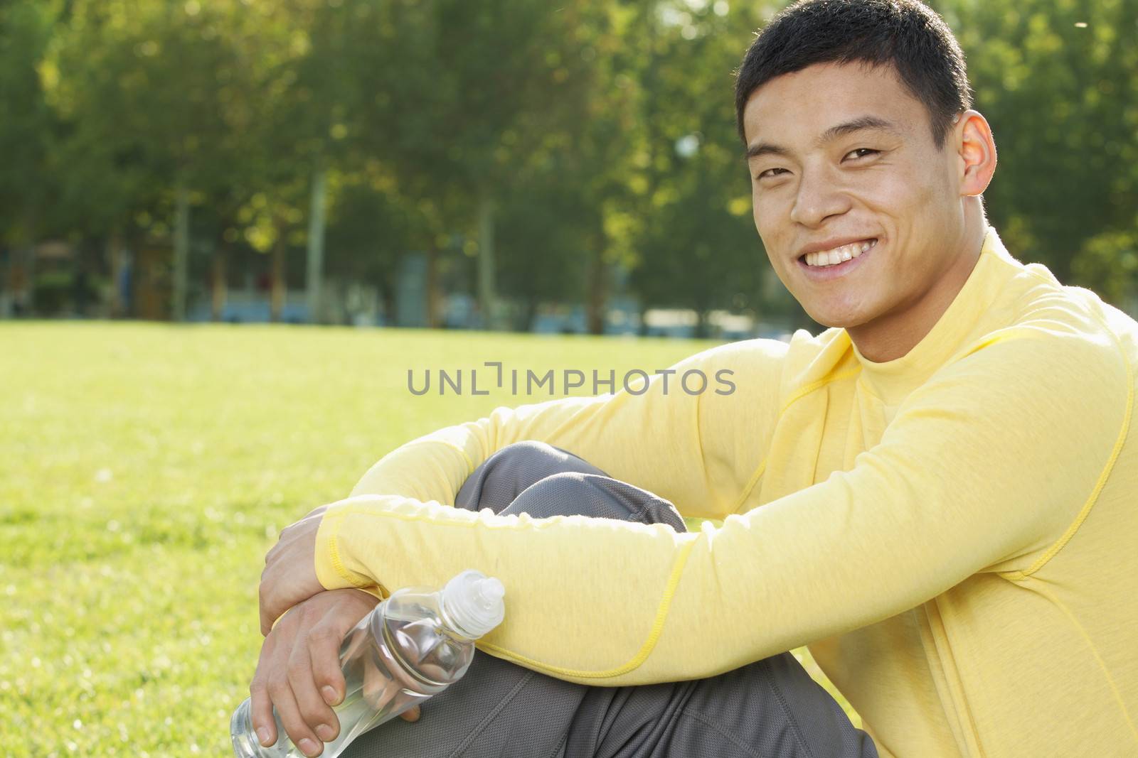 Young Athletic Man Sitting on the Grass in a Park