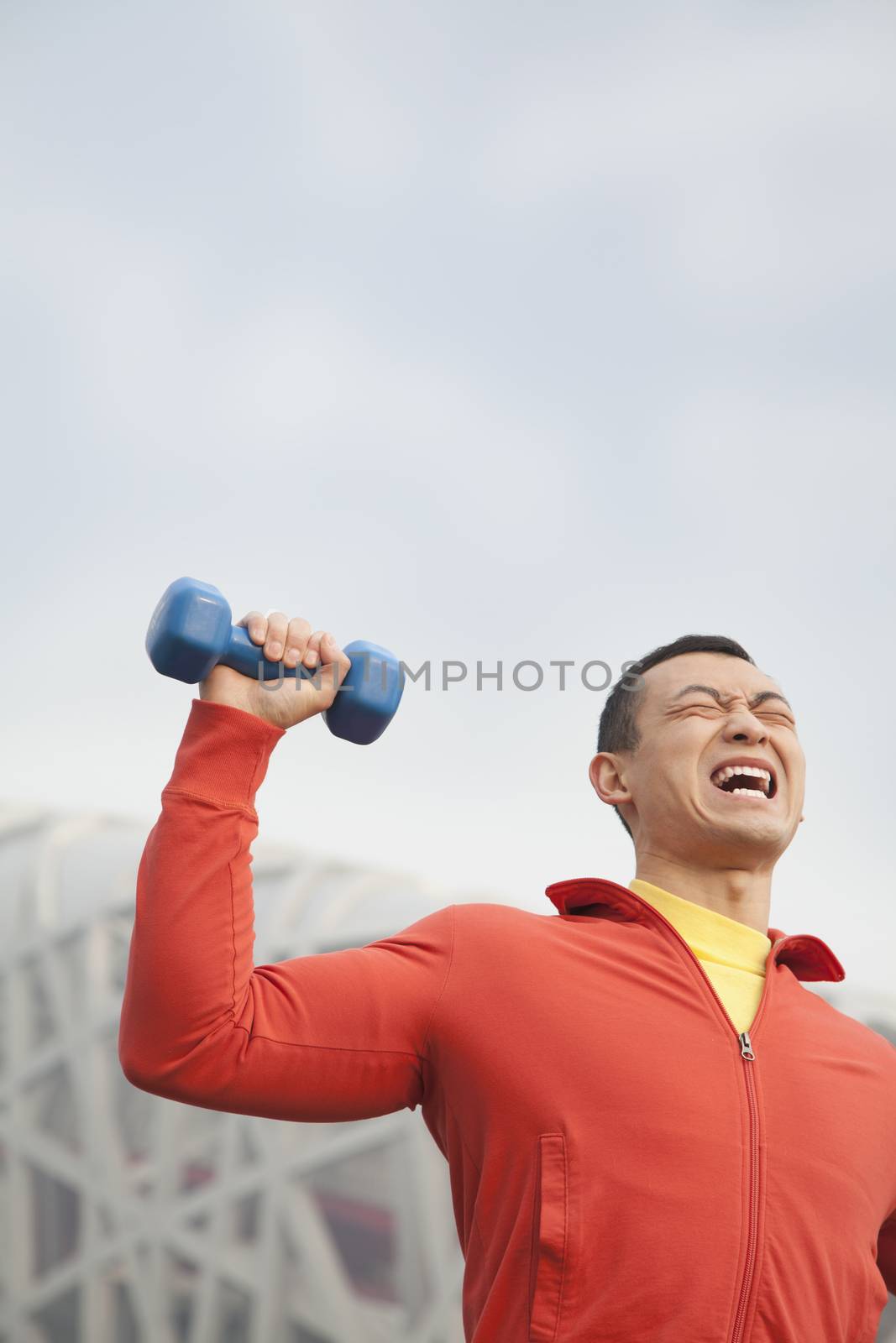 Young man exercising with dumbbells in park, Beijing 