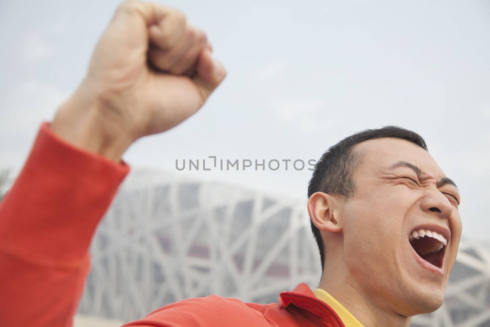 Determined young man with fist in the air, close-up, Beijing