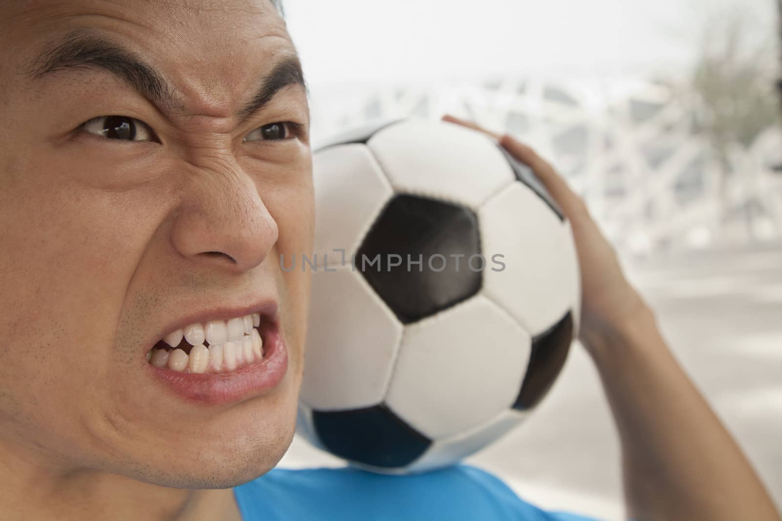 Close up of angry young man holding a soccer ball