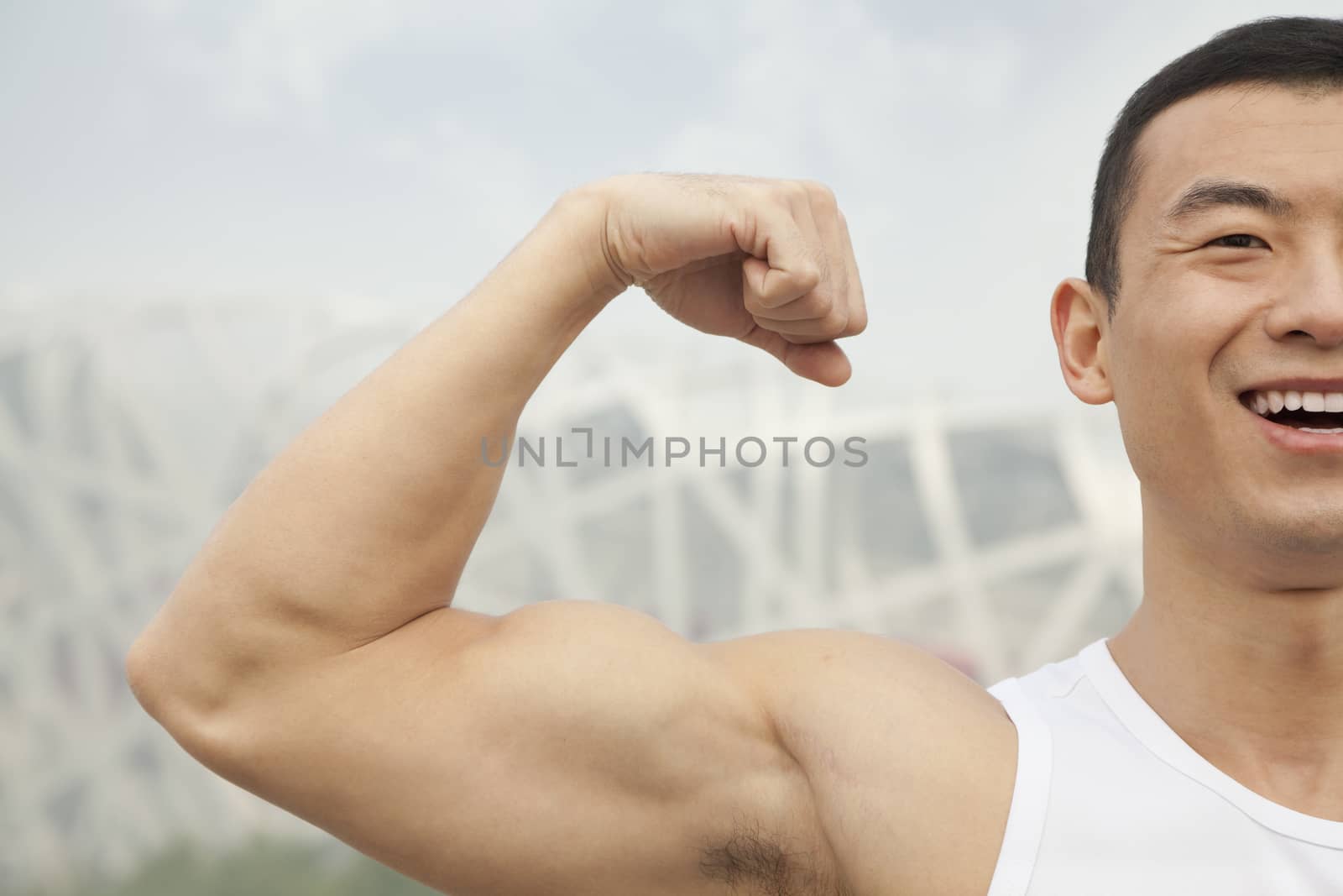Young man smiling and flexing his bicep