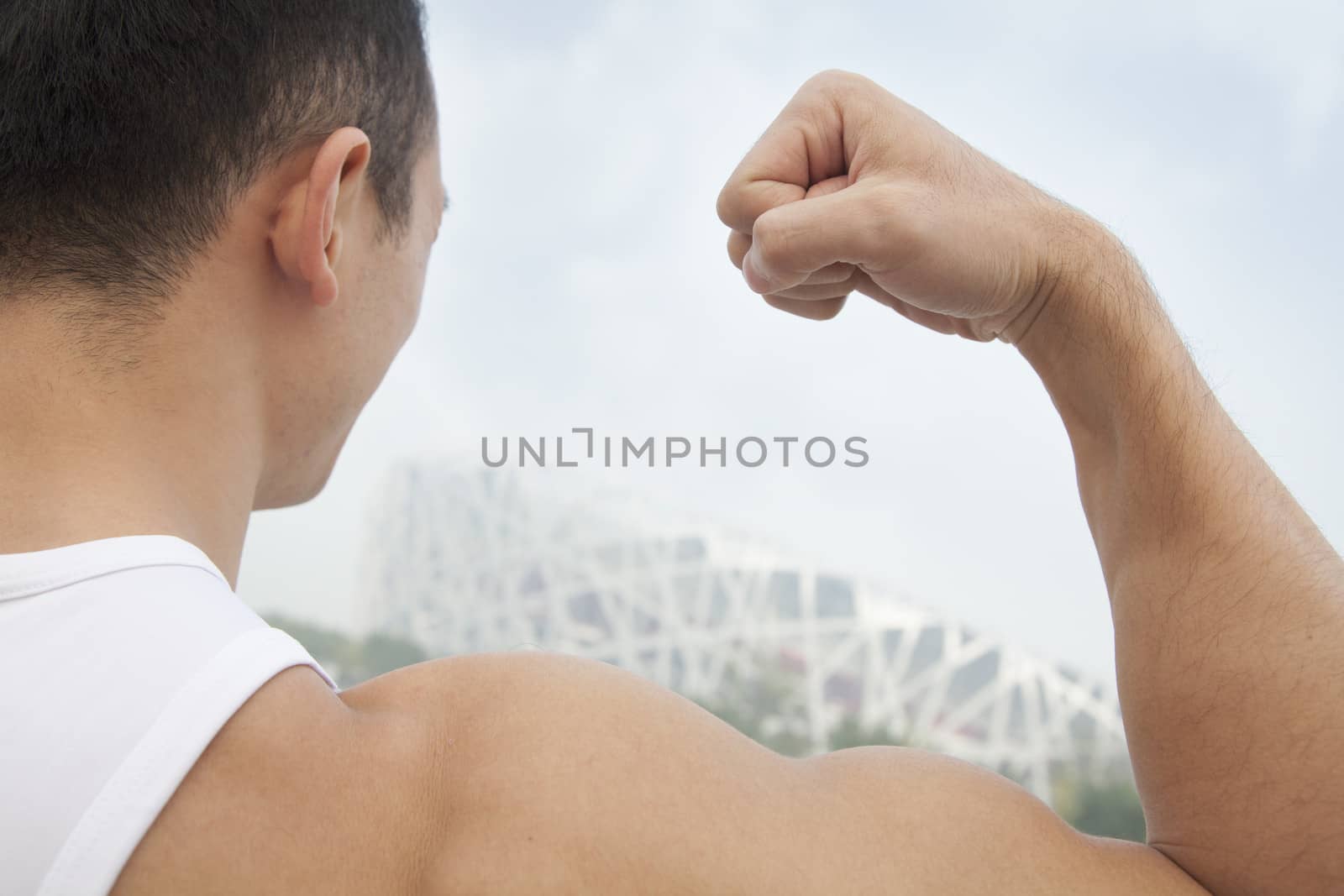 Rear view of young man flexing his bicep, tilt