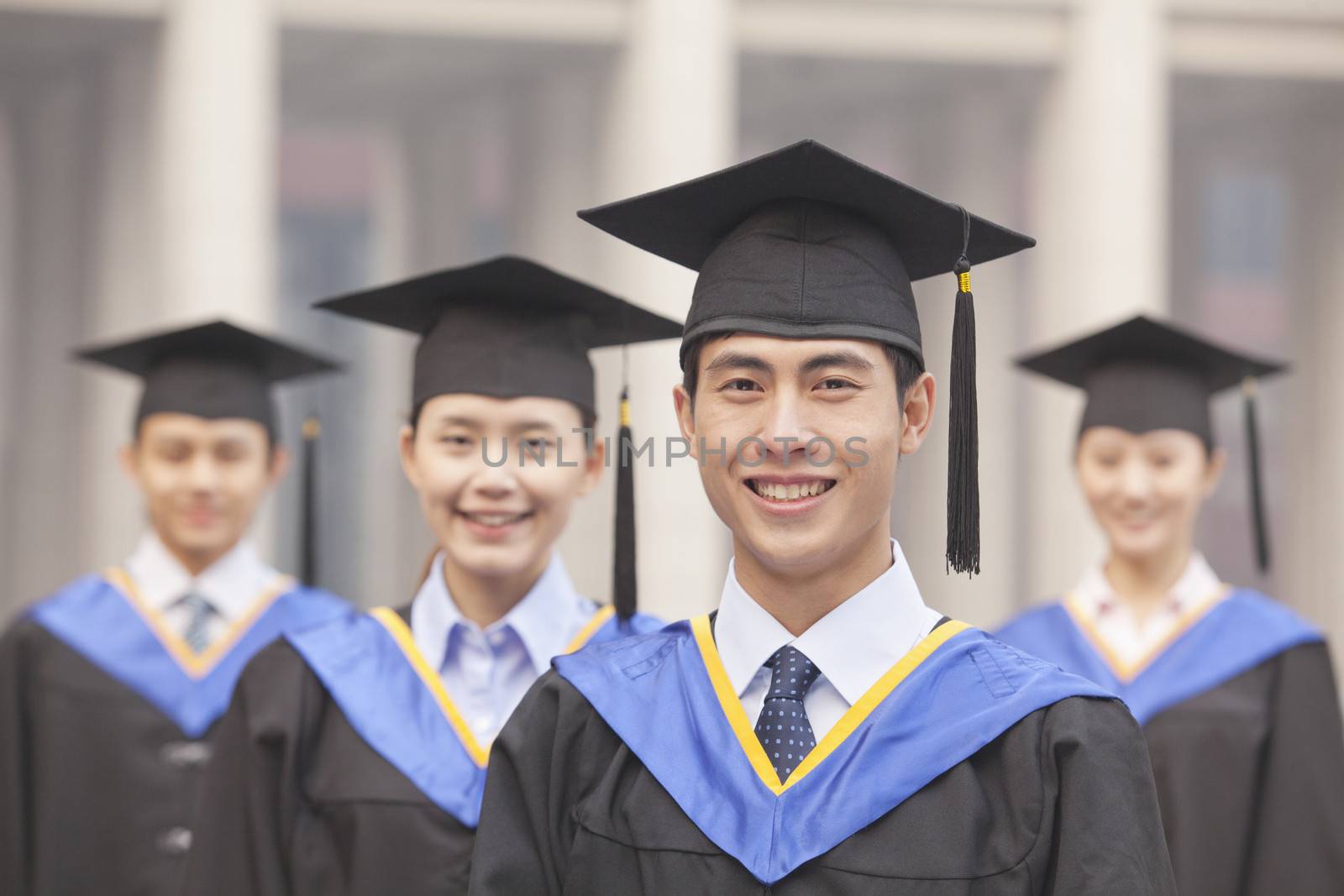  Four University Graduates Smiling, Looking at Camera by XiXinXing