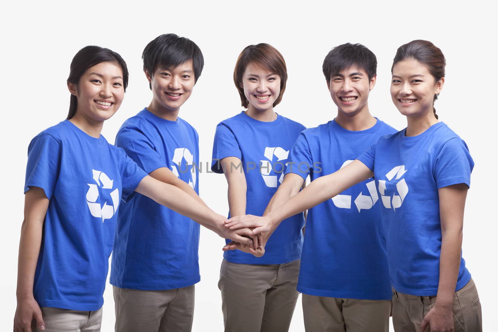 Five young people in recycling t-shirts with hands together, studio shot