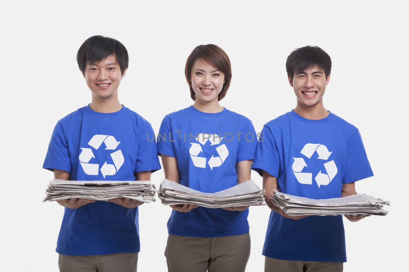 Three young people carrying newspapers, studio shot by XiXinXing