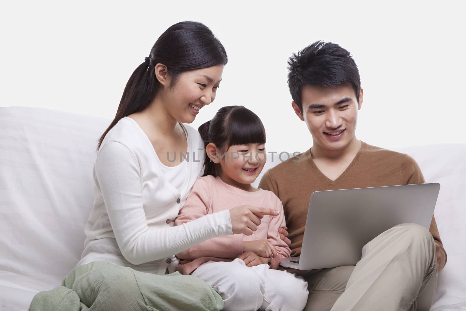 Family sitting on the sofa looking at laptop, studio shot