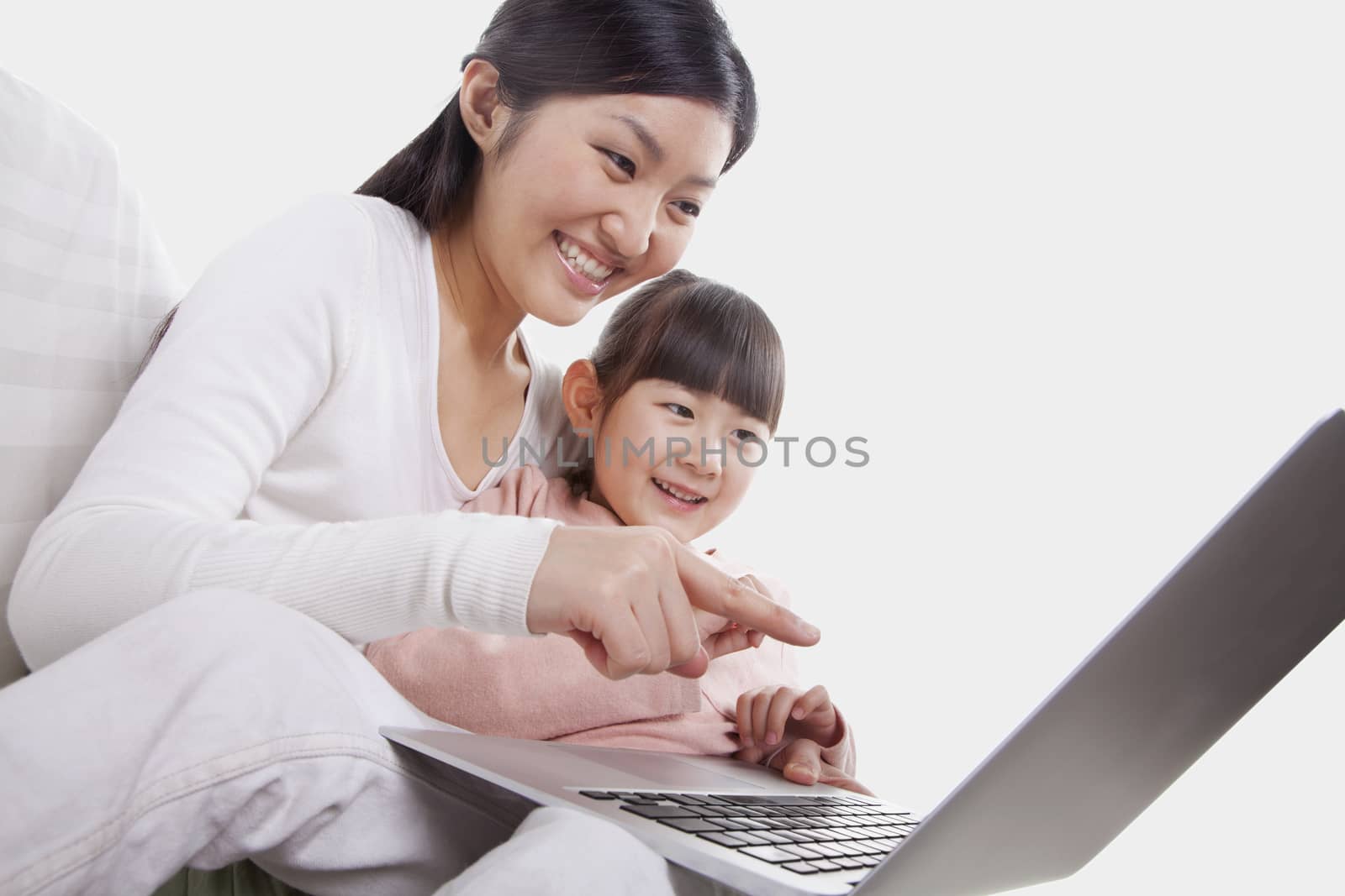 Mother and daughter sitting on sofa using a laptop, tilt by XiXinXing