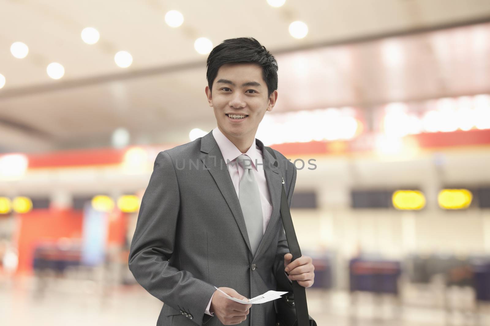 Young businessman holding ticket at the airport, Beijing, China
