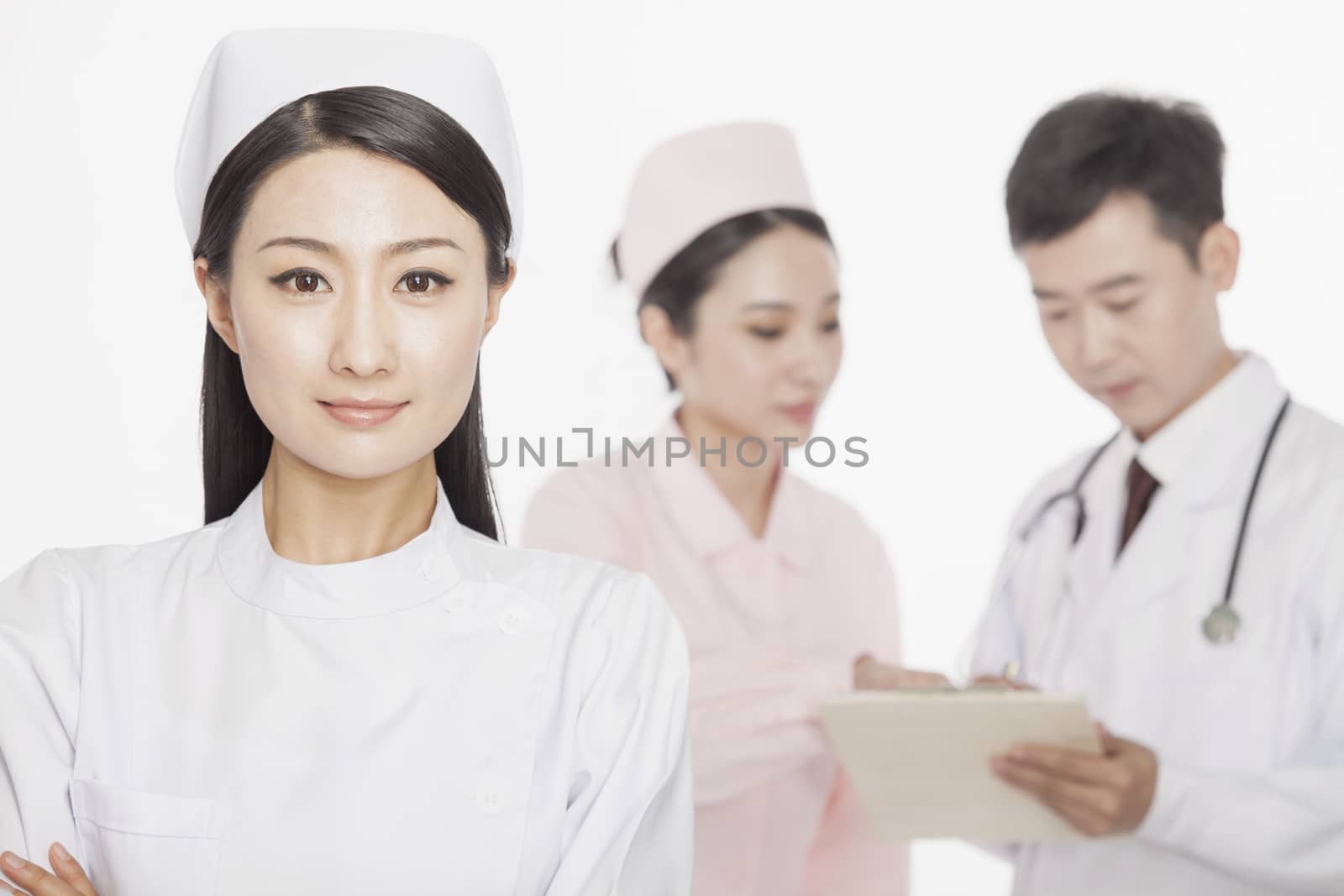 Portrait of young nurse, doctor and nurse in the background, studio shot