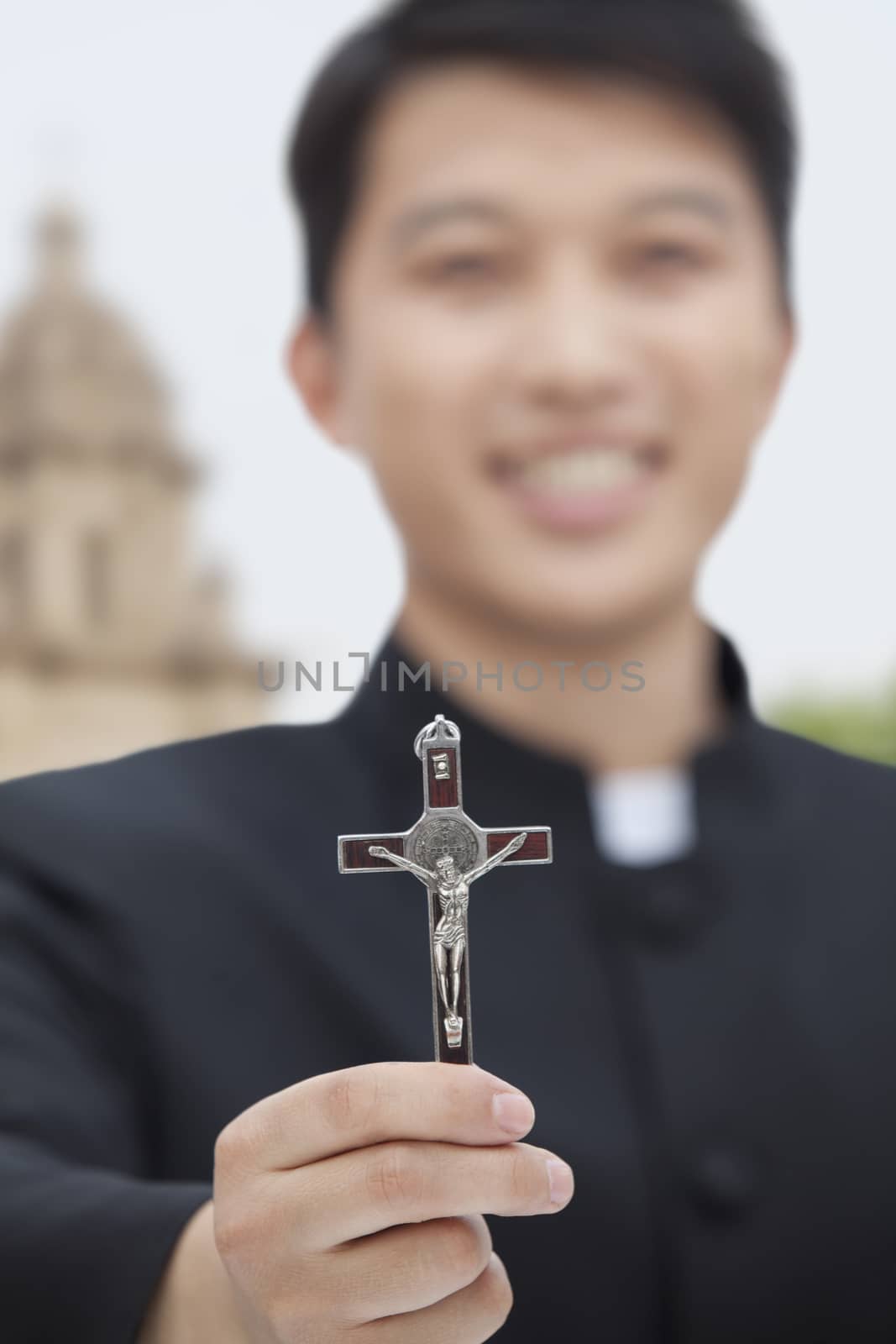 Young Priest Holding Crucifix, Looking at Camera