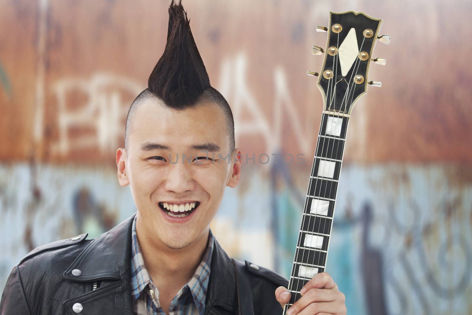 Young man with punk Mohawk holding guitar