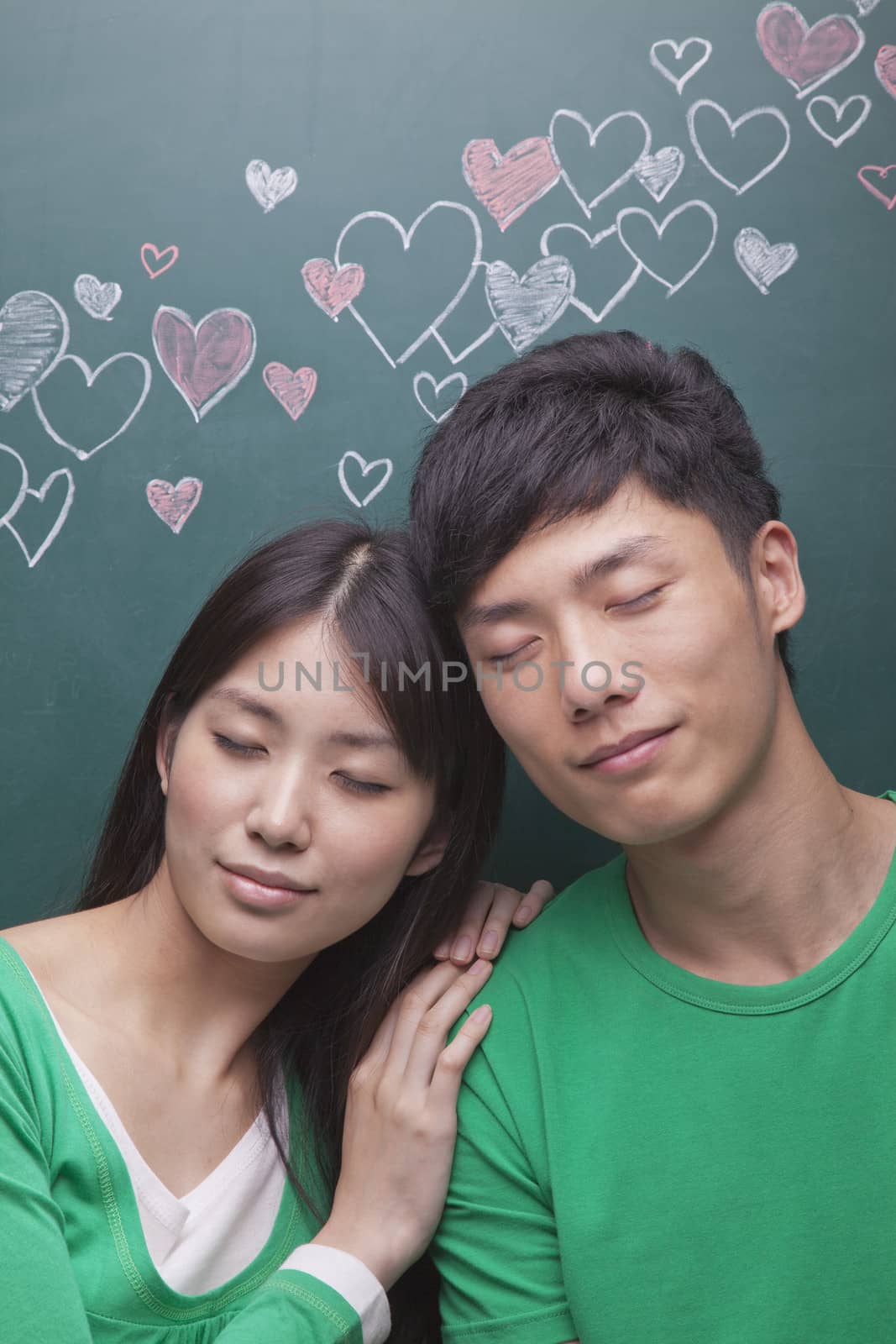Young couple in front of blackboard with hearts    