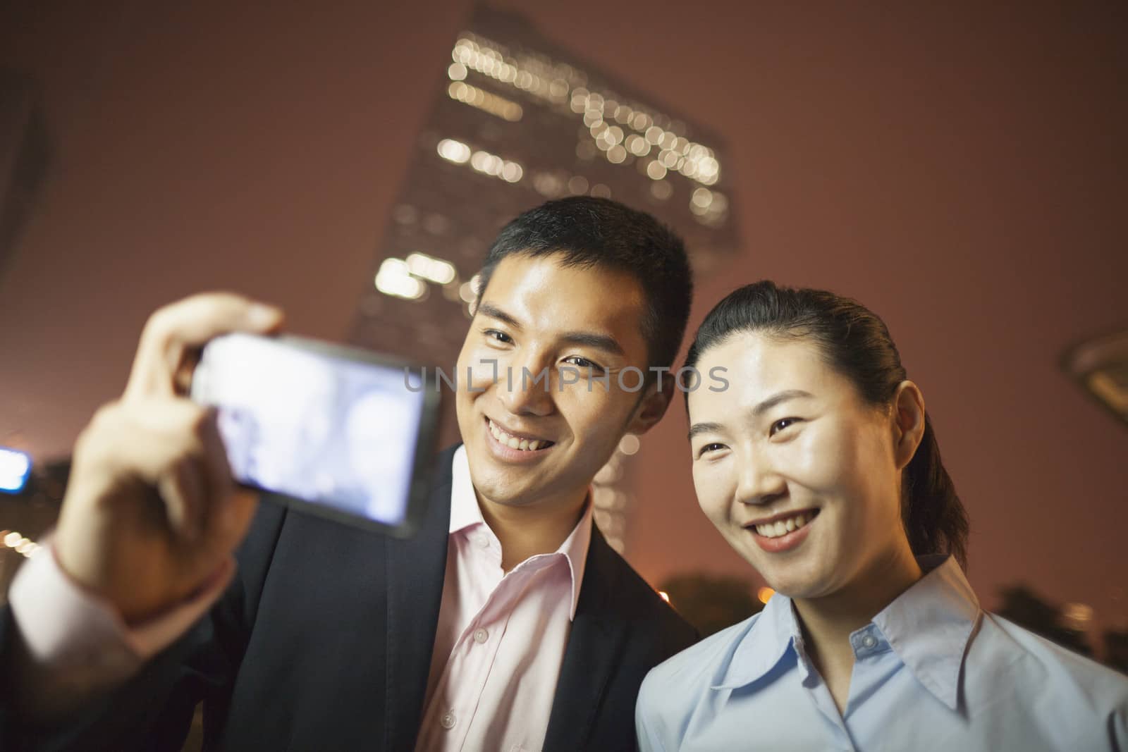 two business people smiling and taking a picture with the phone