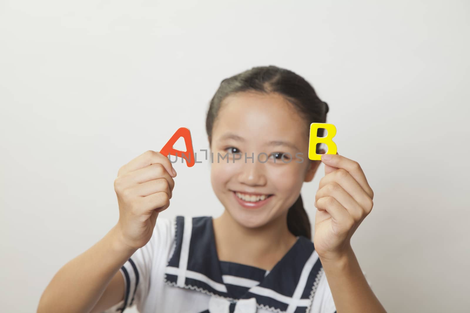 Girl smiling and holding plastic letters, Studio