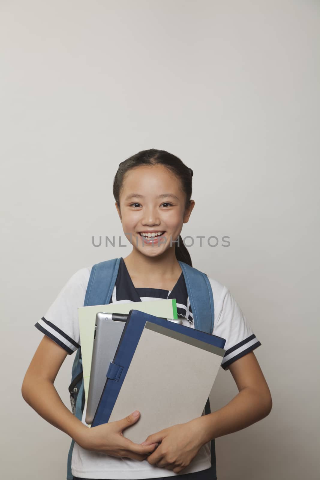 Girl smiling and holding bunch of notebooks and digital tablet, Studio