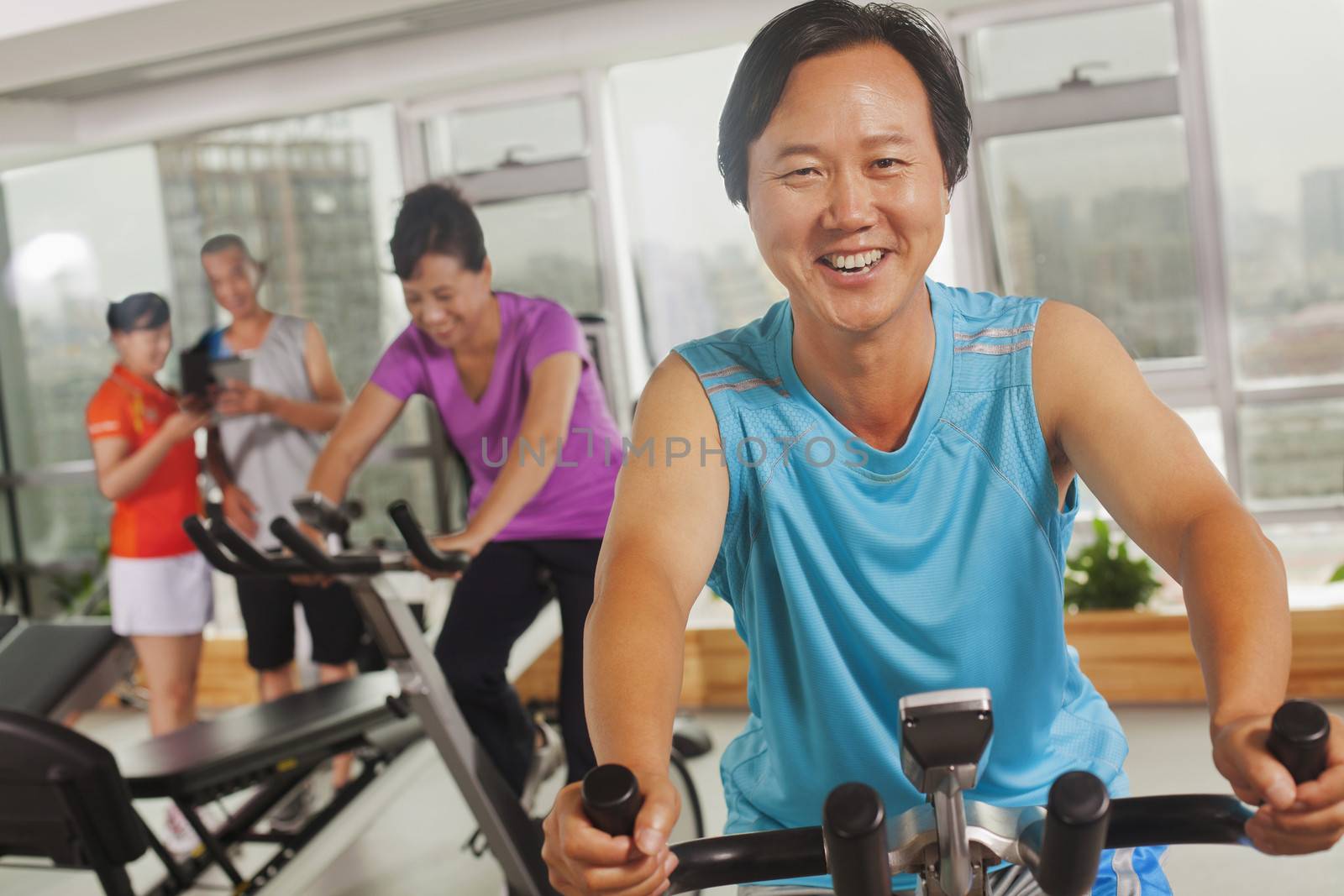 Man smiling and exercising on the exercise bike by XiXinXing