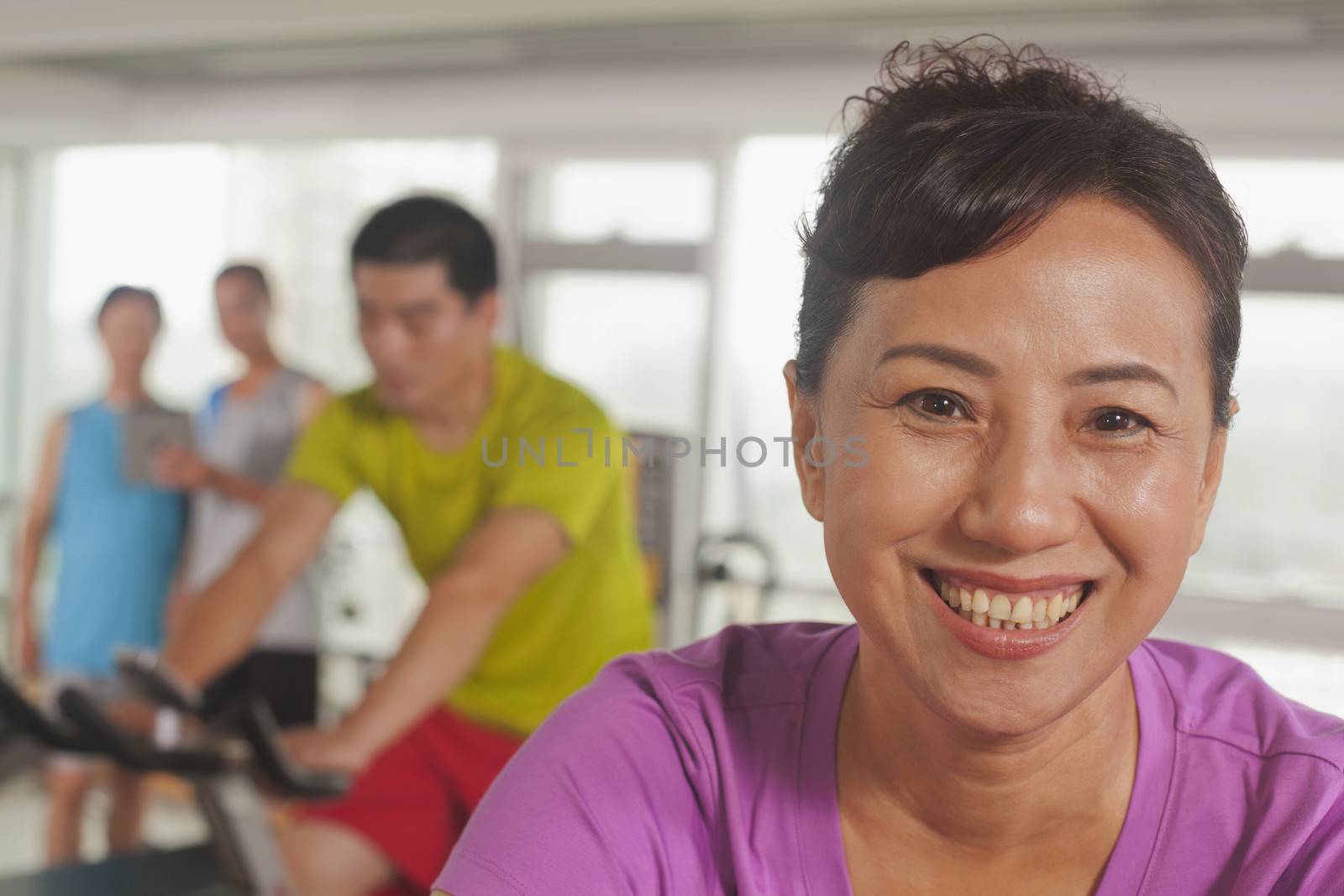 Woman smiling and exercising on the exercise bike by XiXinXing