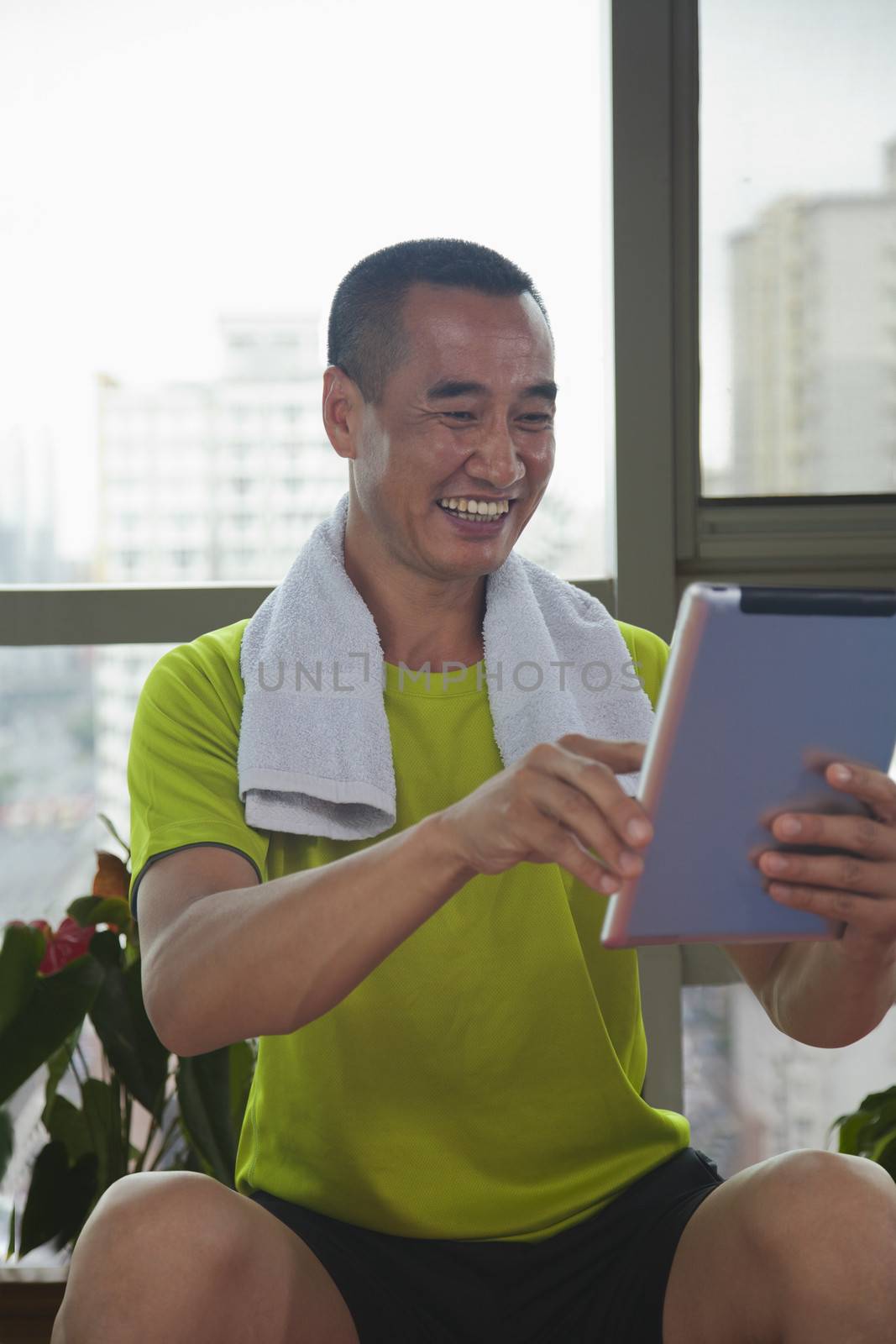 Mature man looking at his digital tablet in the gym