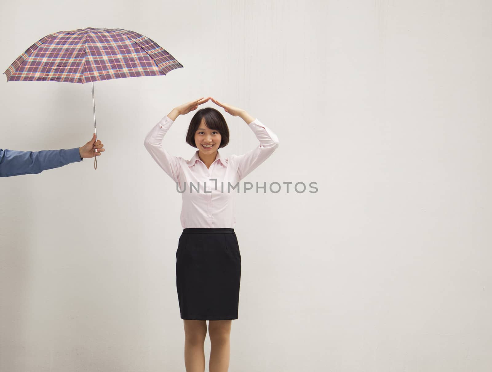 Young businesswoman with her hand above head, co-worker giving her umbrella