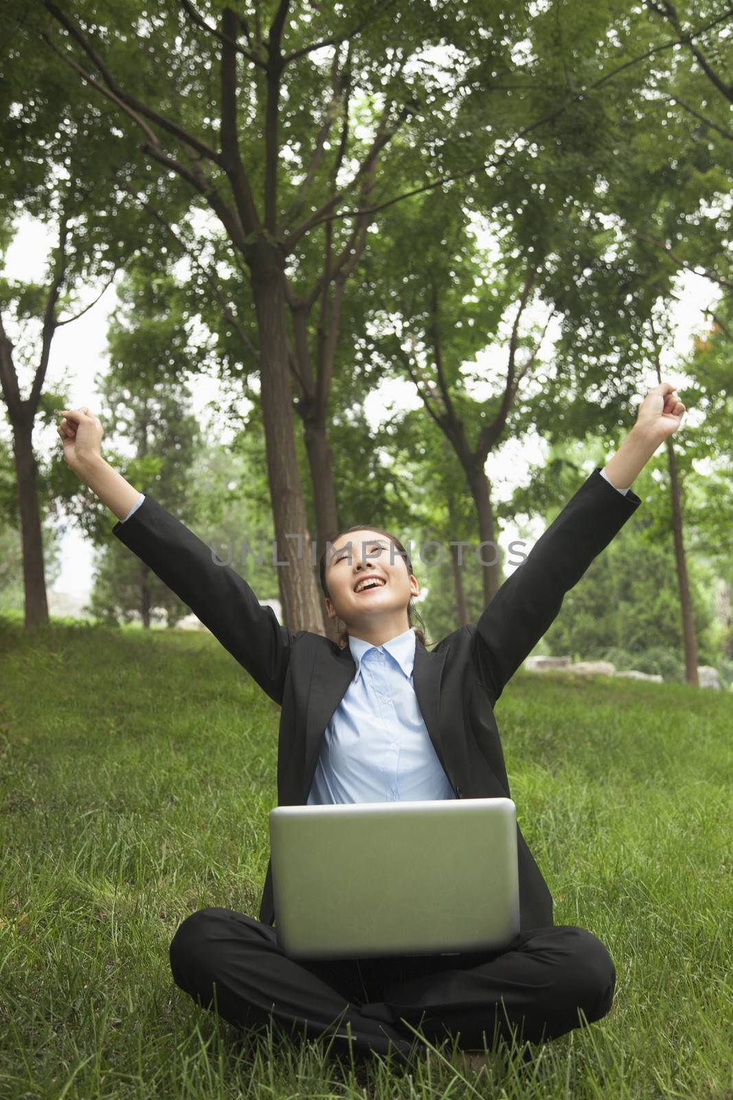 Young businesswoman sitting in the park and stretching