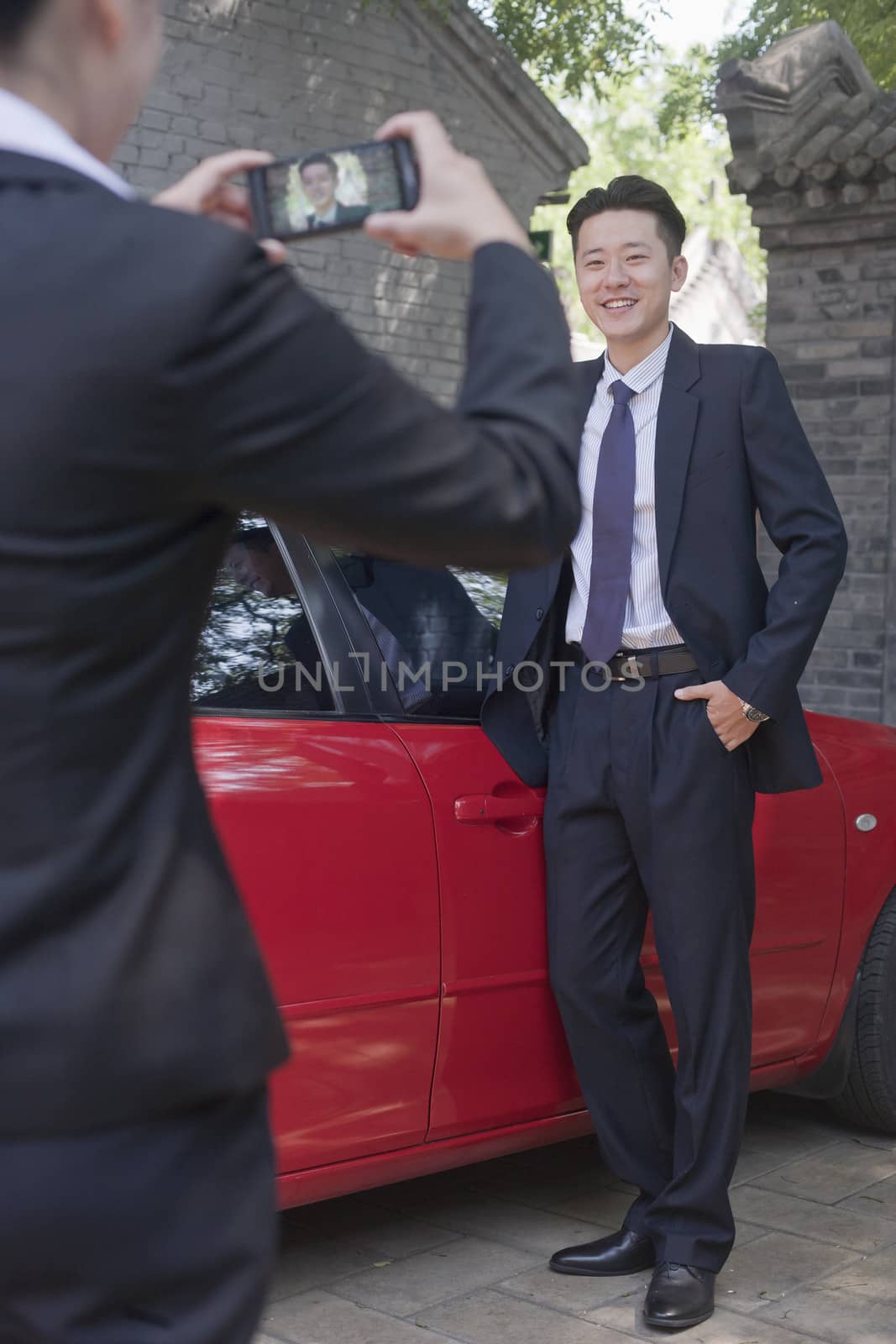 Businesswoman Taking Businessman's Picture Next to His Car