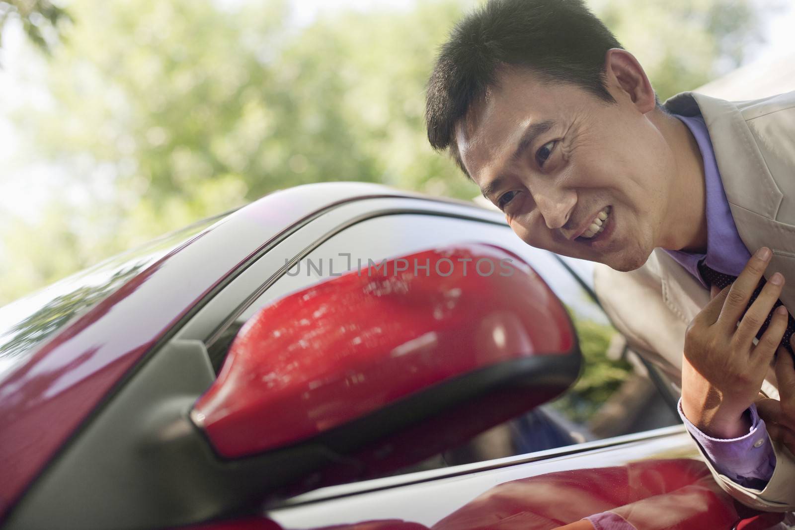 Businessman Adjusting Tie in Car Mirror