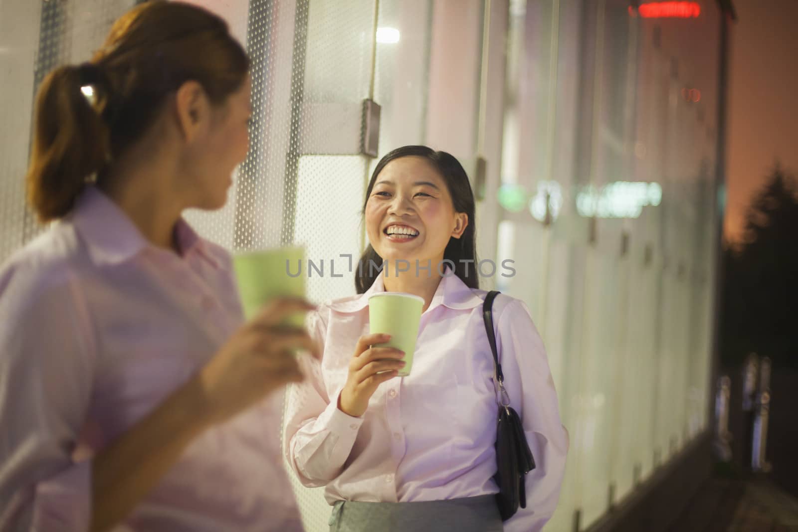 Young businesswomen smiling and drinking coffee outdoor