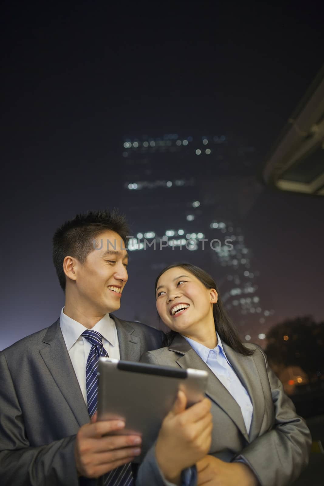 Young business people smiling and holding digital tablet