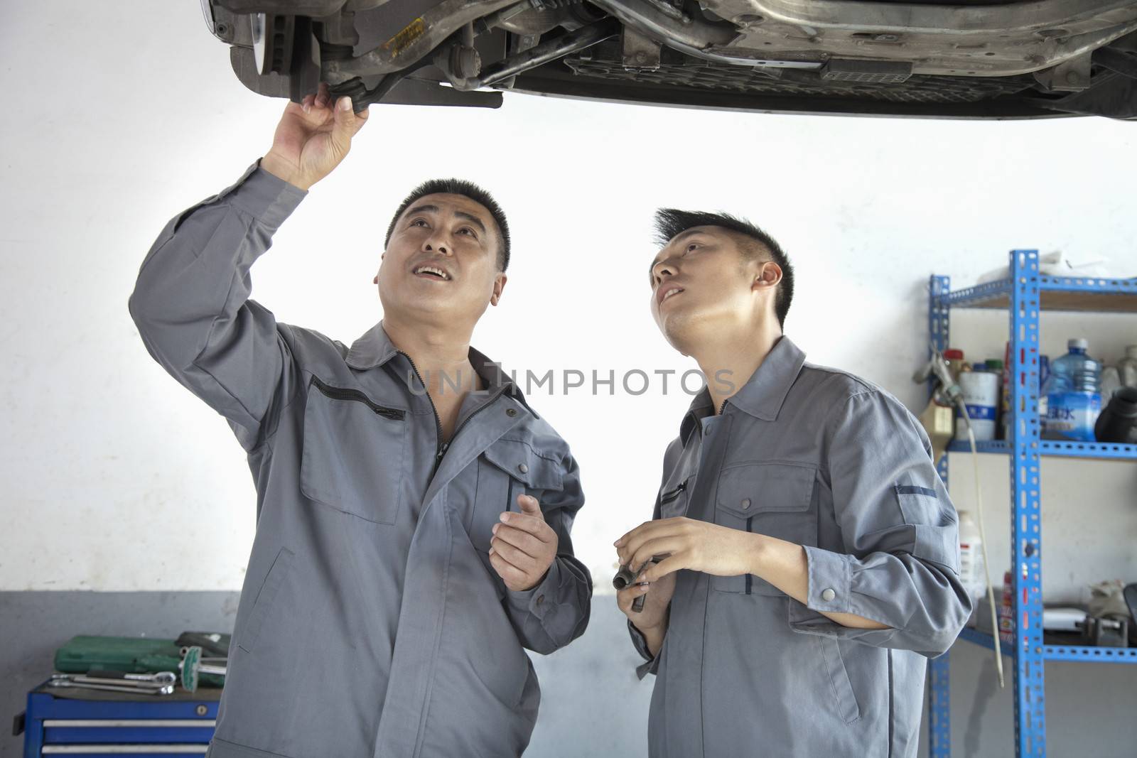 Two Mechanics Looking at Underside of a Car by XiXinXing