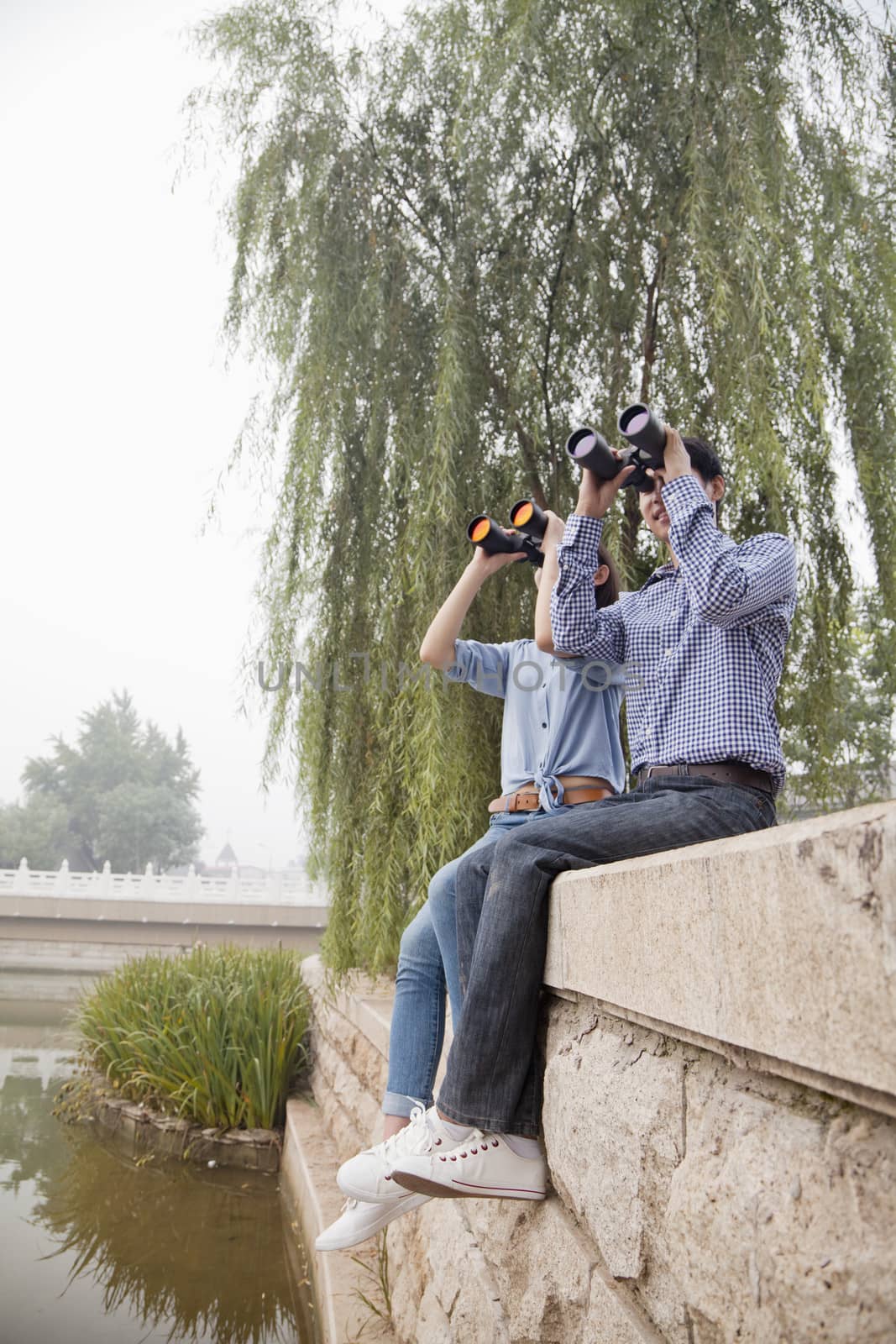 Young Couple Looking Out With Binoculars