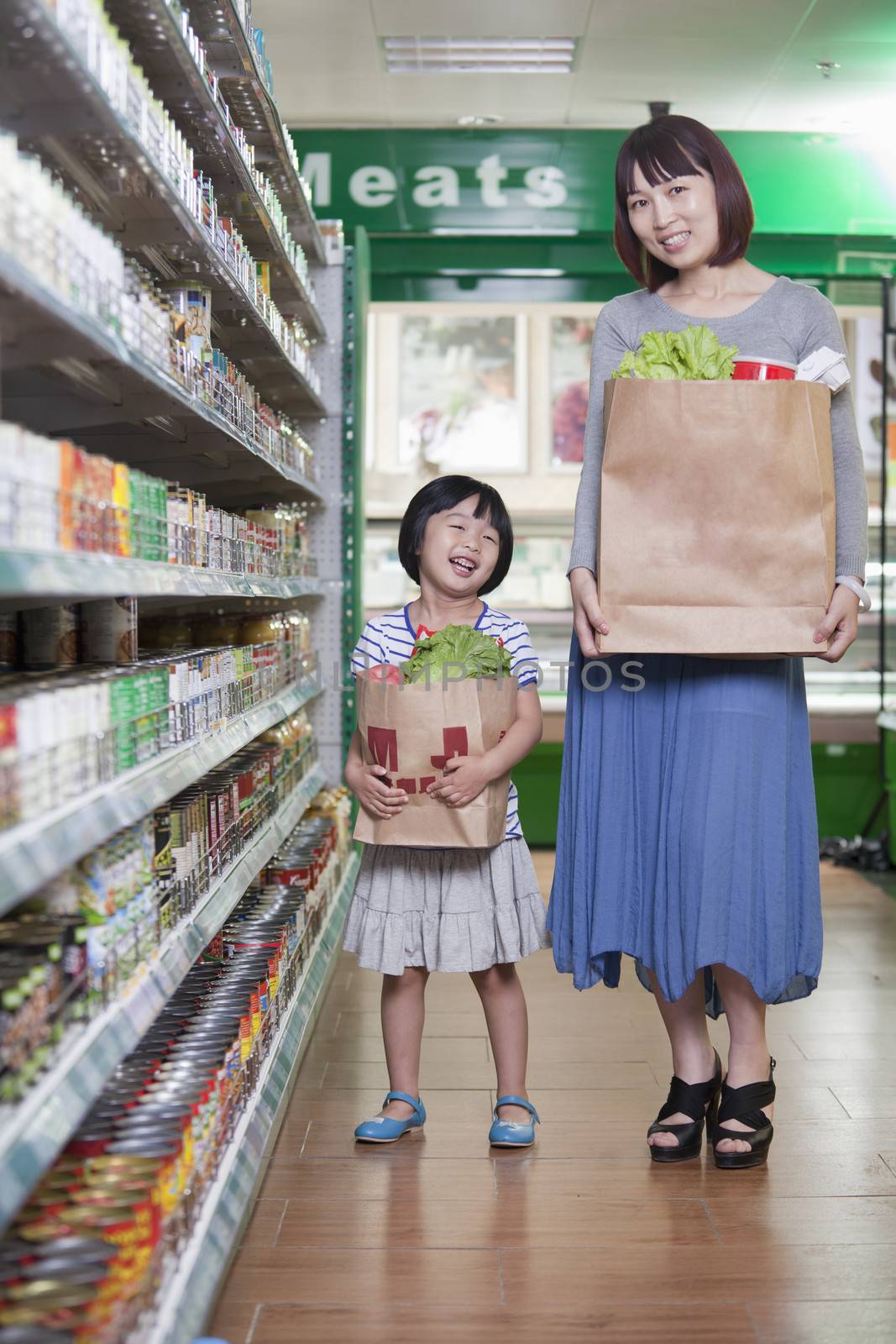 Mother and daughter holding grocery bags in supermarket, Beijing