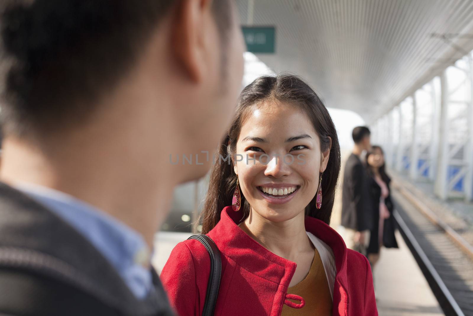 Young woman talking to man on railway platform, China by XiXinXing
