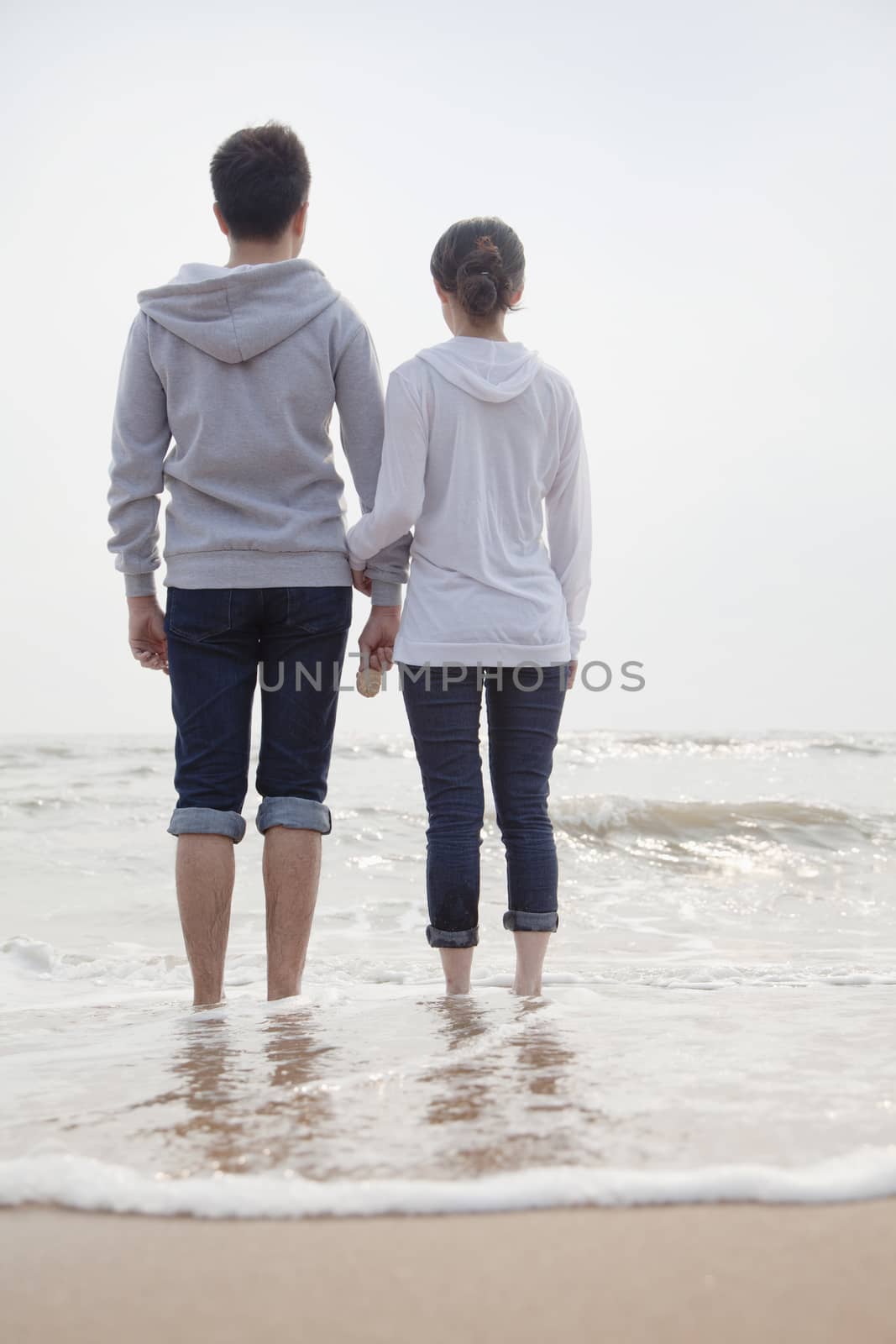 Young couple standing on the beach and looking out to sea      by XiXinXing