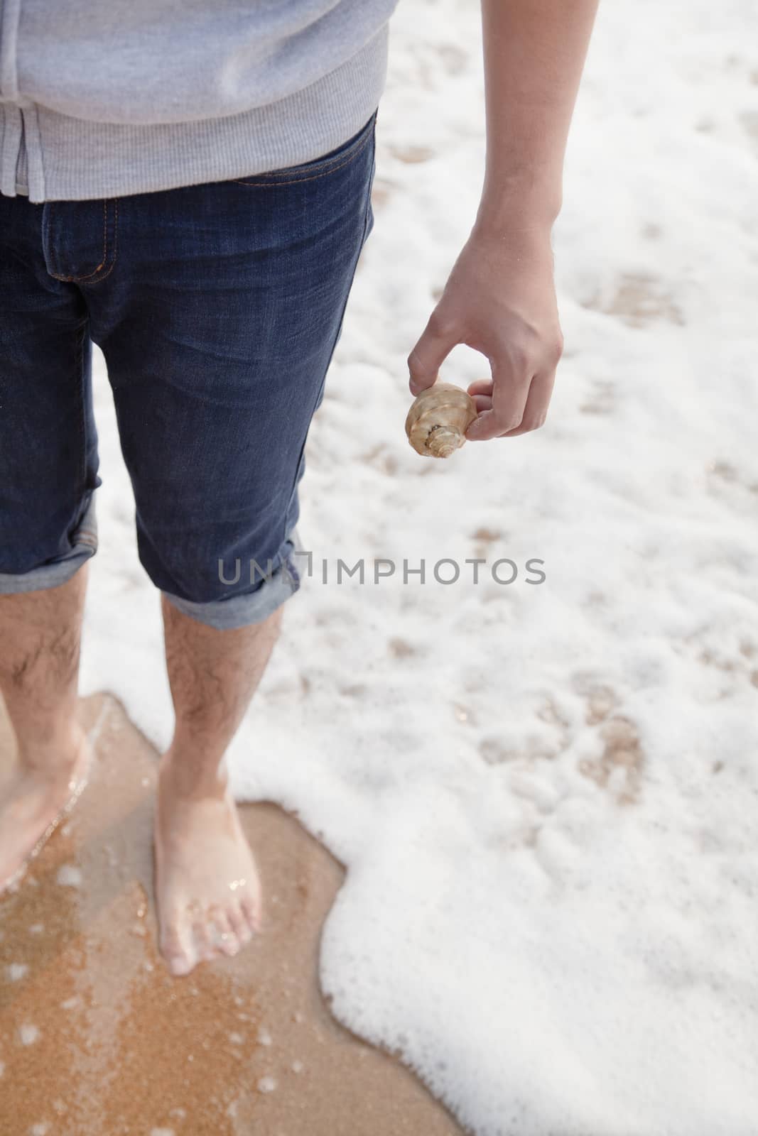 Young man holding a seashell, high angle view  