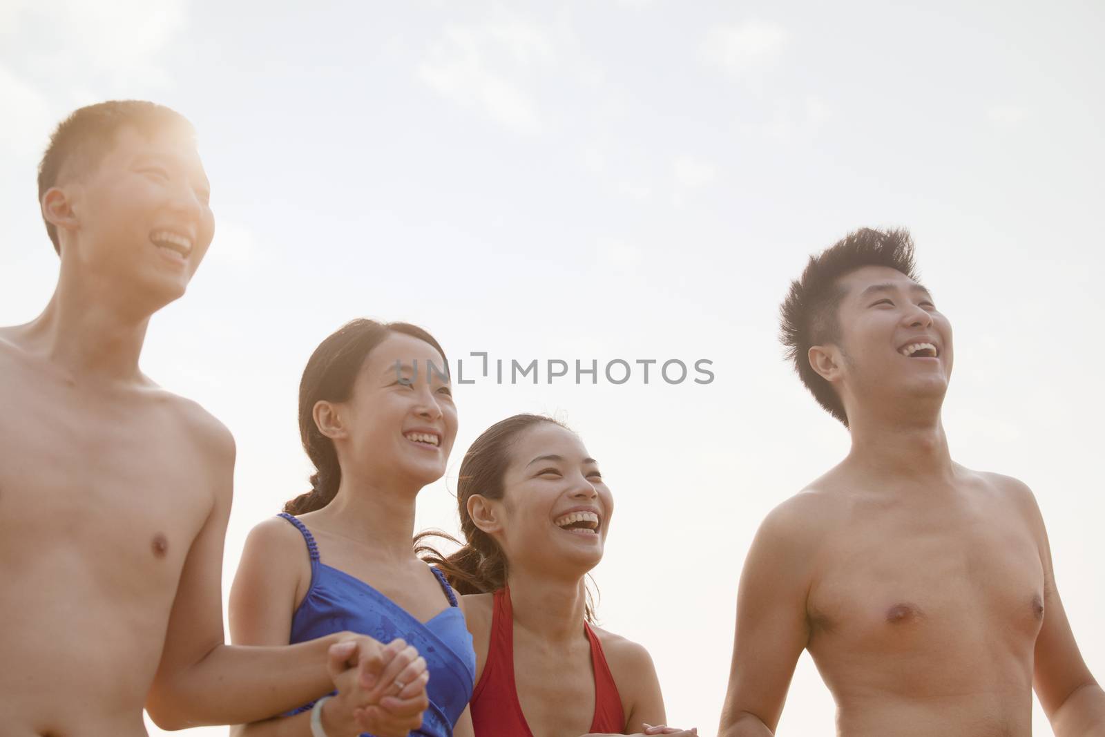 Four friends smiling and laughing on the beach