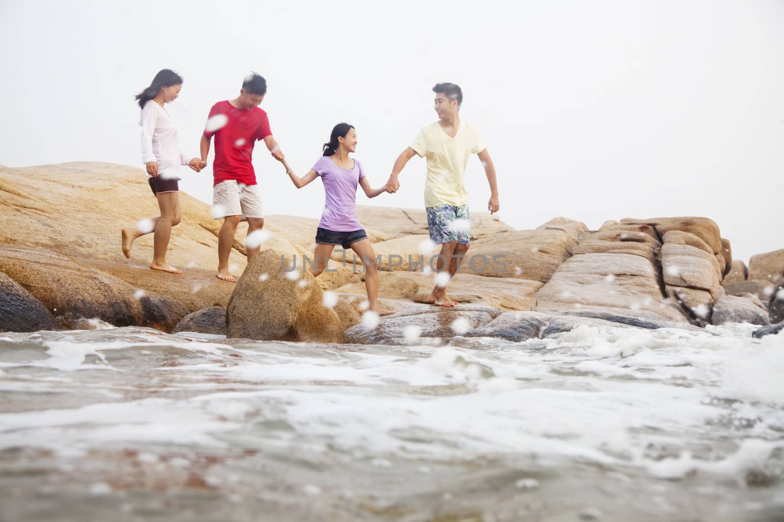 Four friends walking over rocks by the sea by XiXinXing